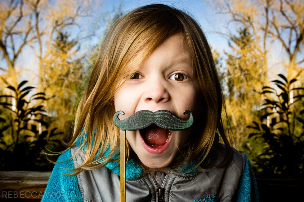Off Camera Flash Image of young girl in color holding mustache prop