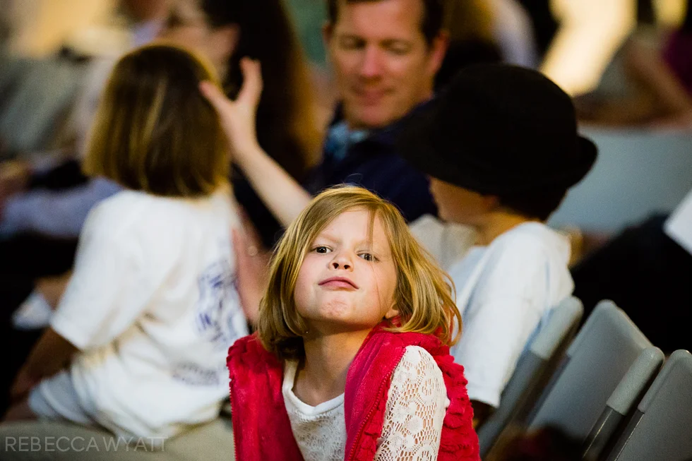 Girl sitting in an audience pouting at the camera.
