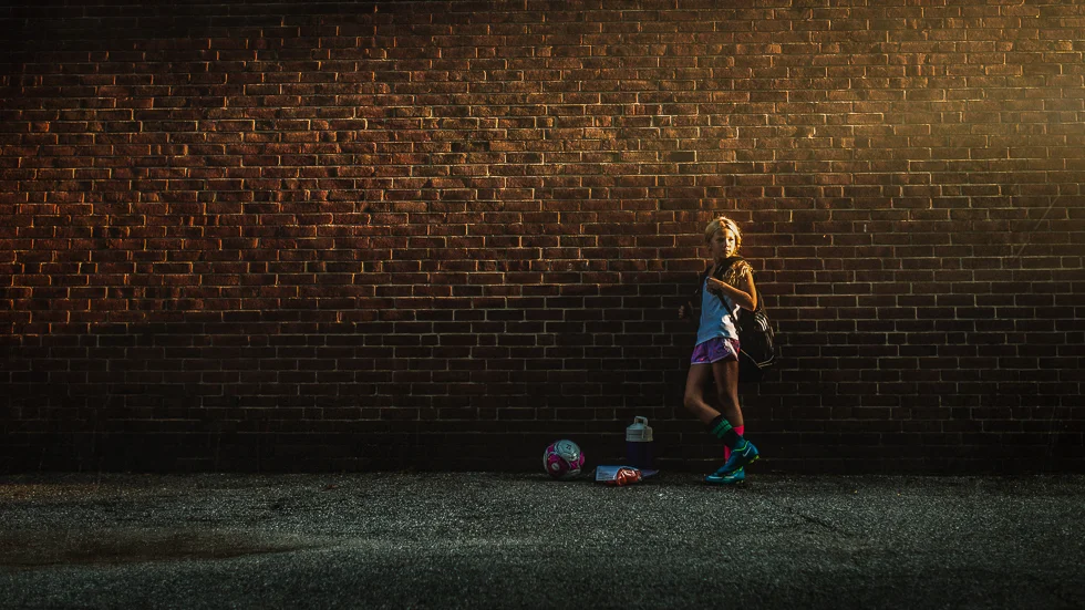 soccer player against wall in evening light