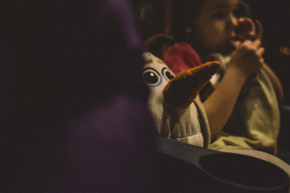 girl and stuffed olaf sitting in the movie theater.