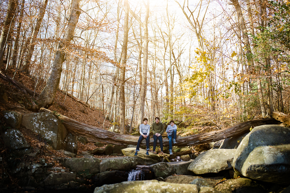 Copy of Golden light in photograph of three brothers sitting on log over a stream in the woods.