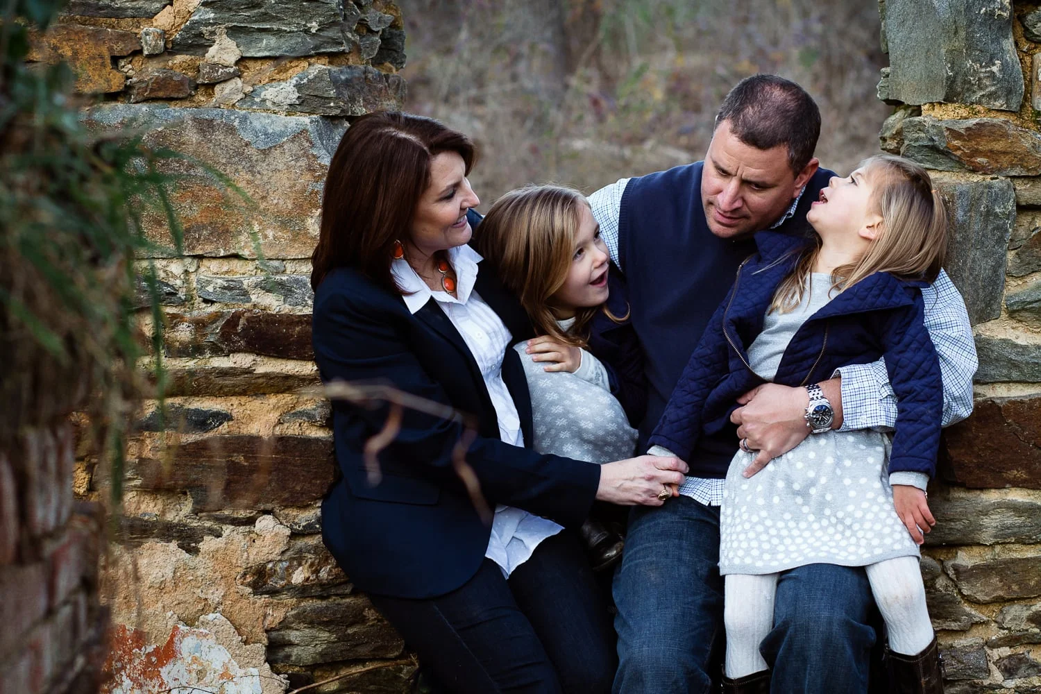 attractive family with two daughters laughing and smiling in family portrait.