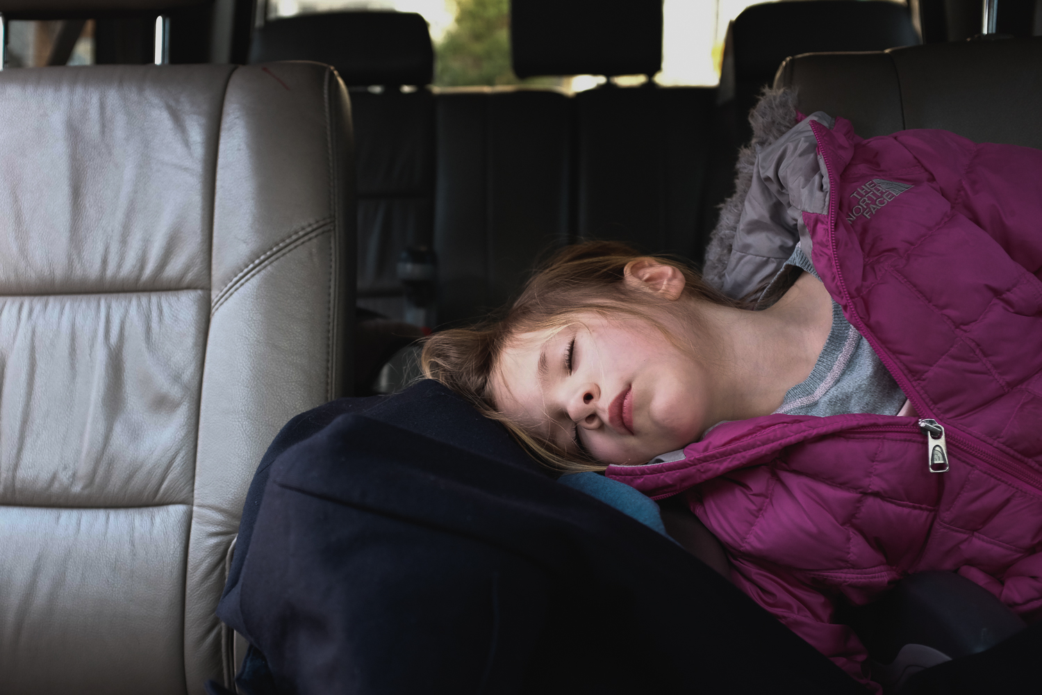 preschool child napping in backseat of mother's car after school.