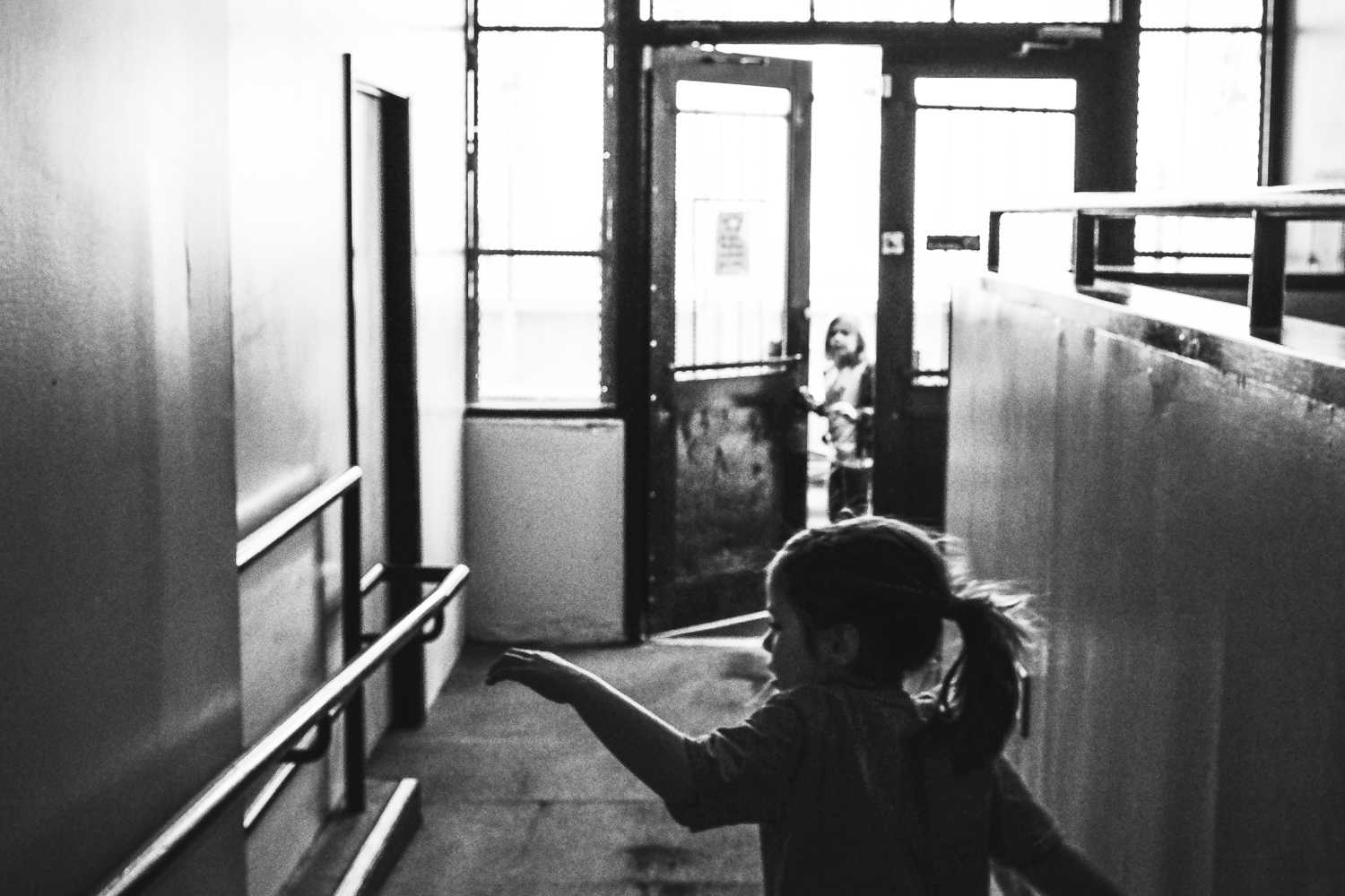 black and white photo girl walking towards her sister at ice skating rink