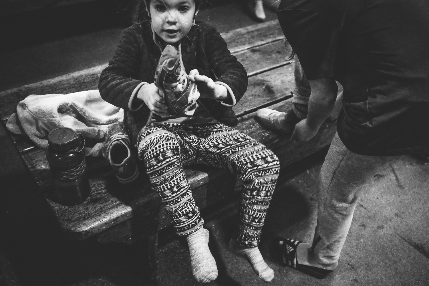 young child putting on her shoes after removing her skates 