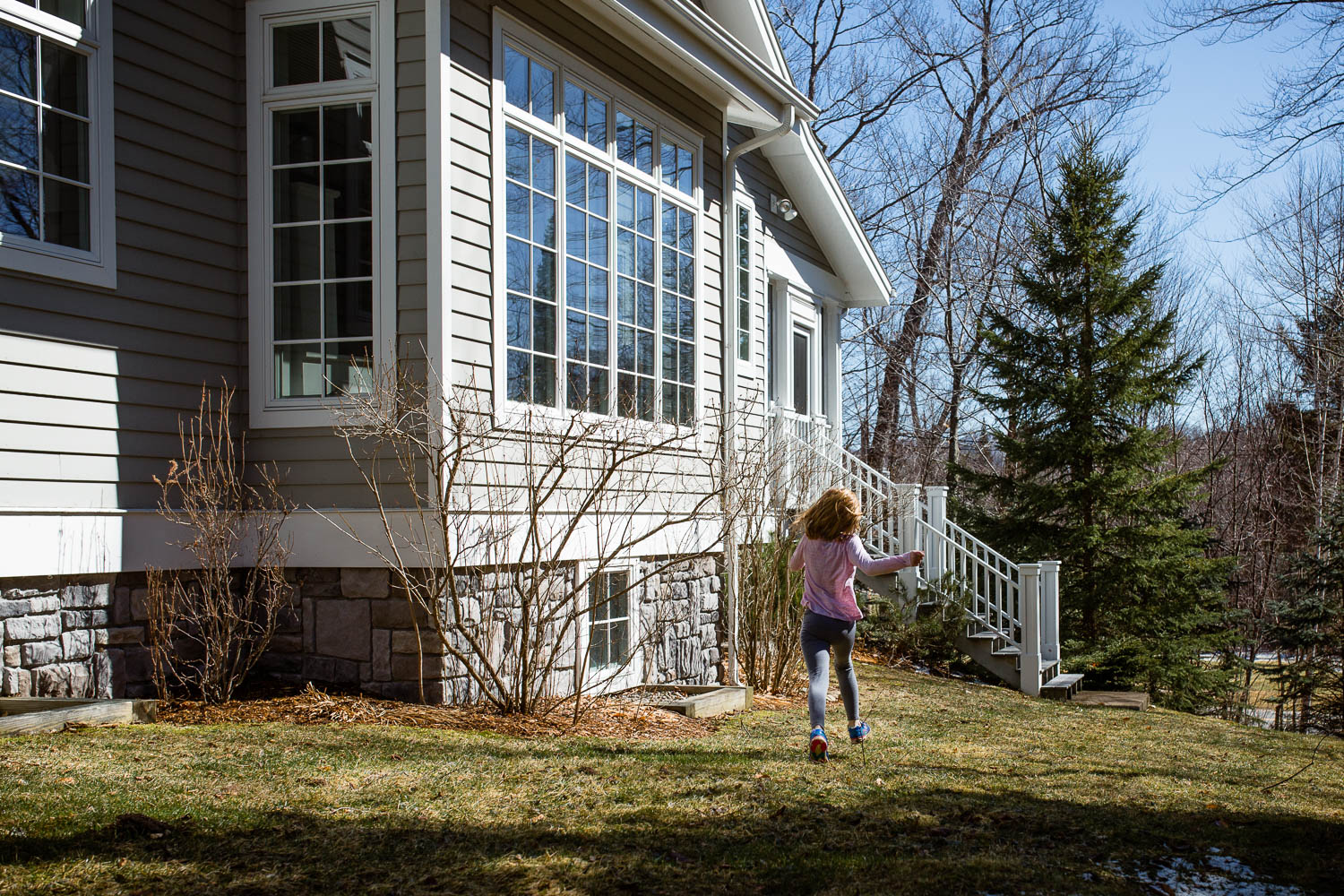 child in pink shirt running outside house in woods