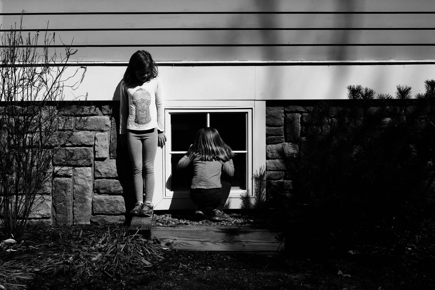 two girls beside a house playing a game in black and white photograph