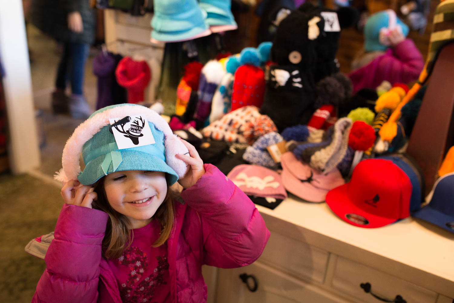 child trying on a blue hat and earmuffs in hat shop