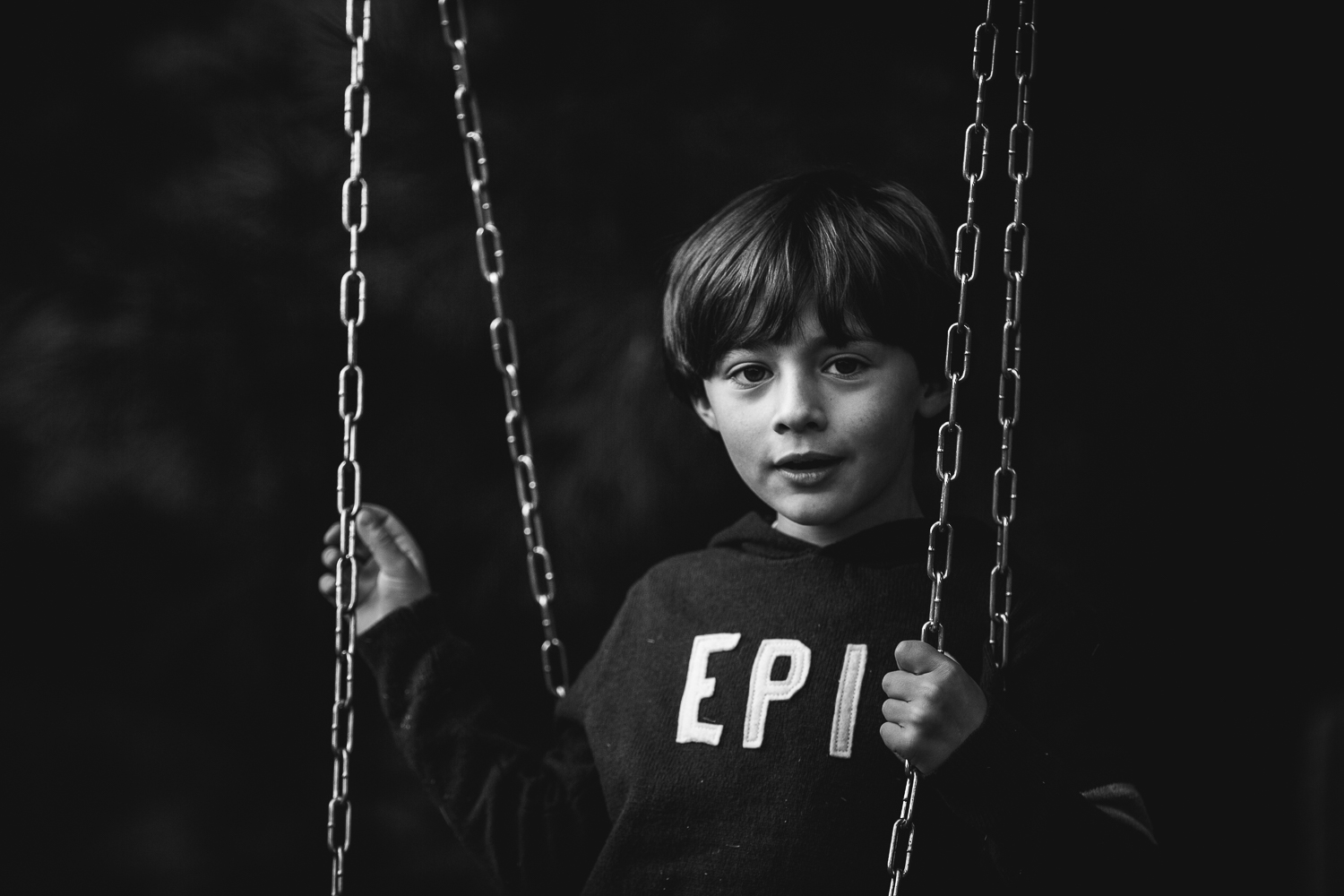  boy in tire swing holding chains 