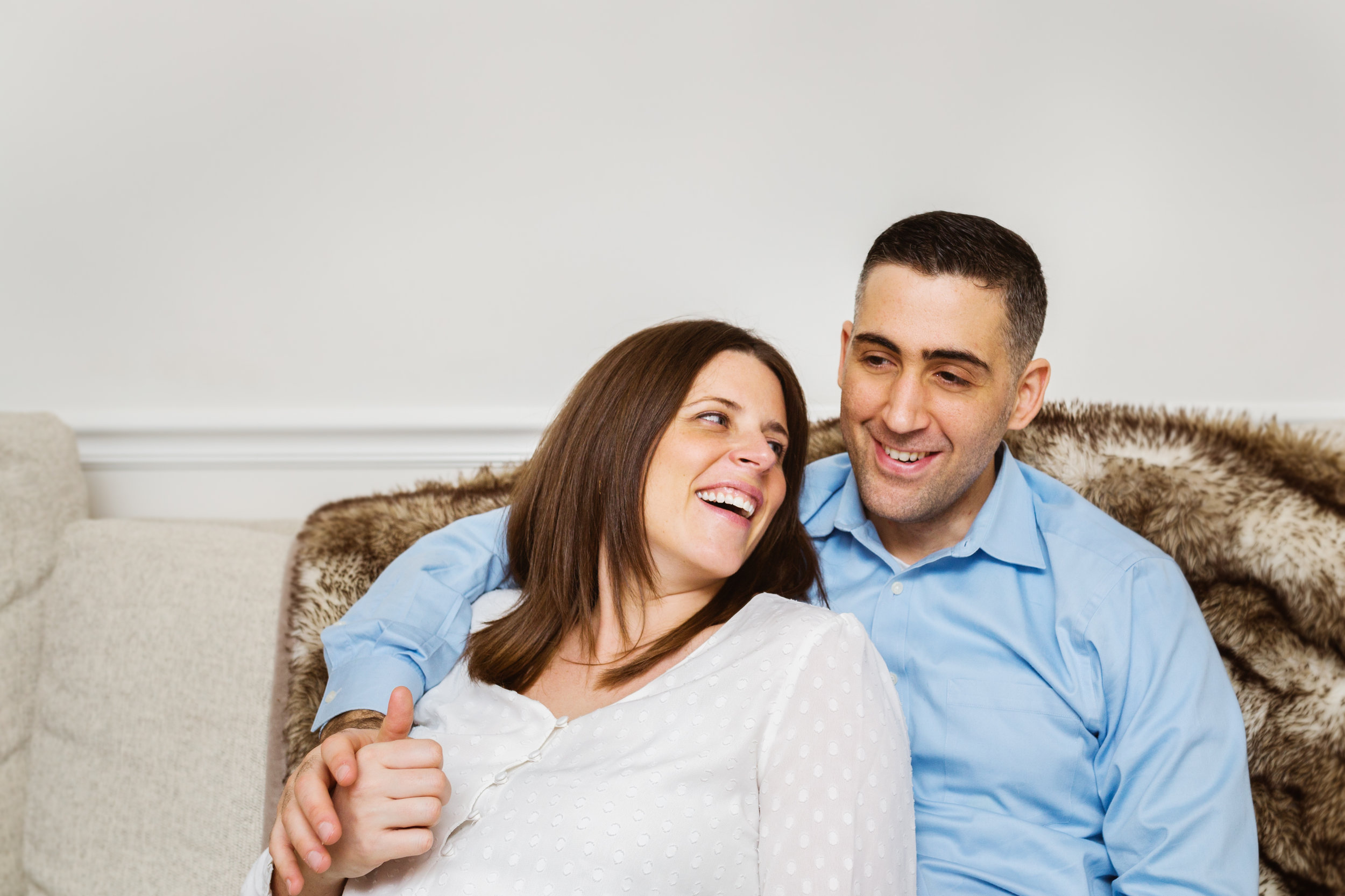 expectant parents snuggle on sofa