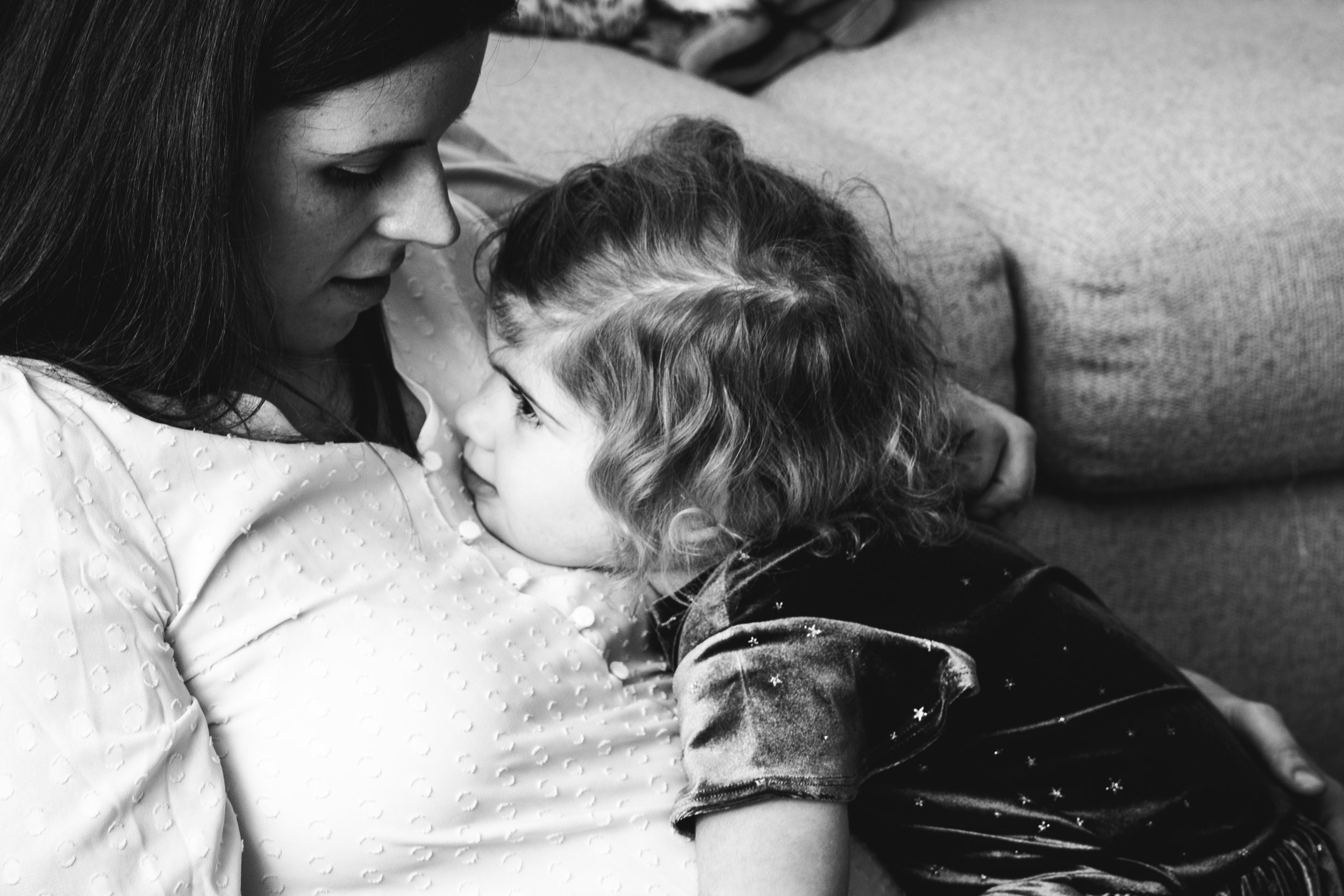 little girl snuggles with her mother in black and white family photo