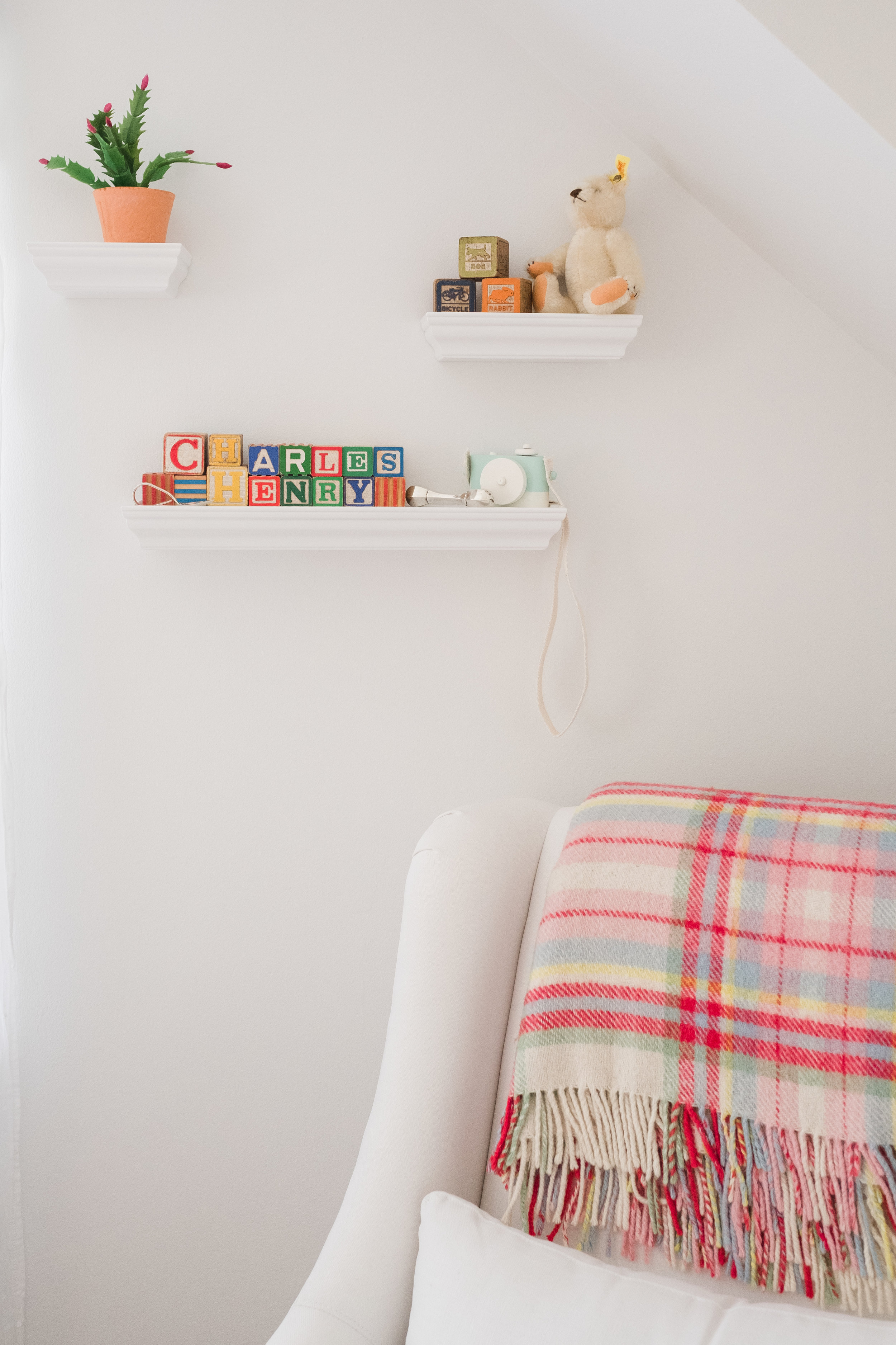 view of colorful blanket draped over white chair in baby boy nursery