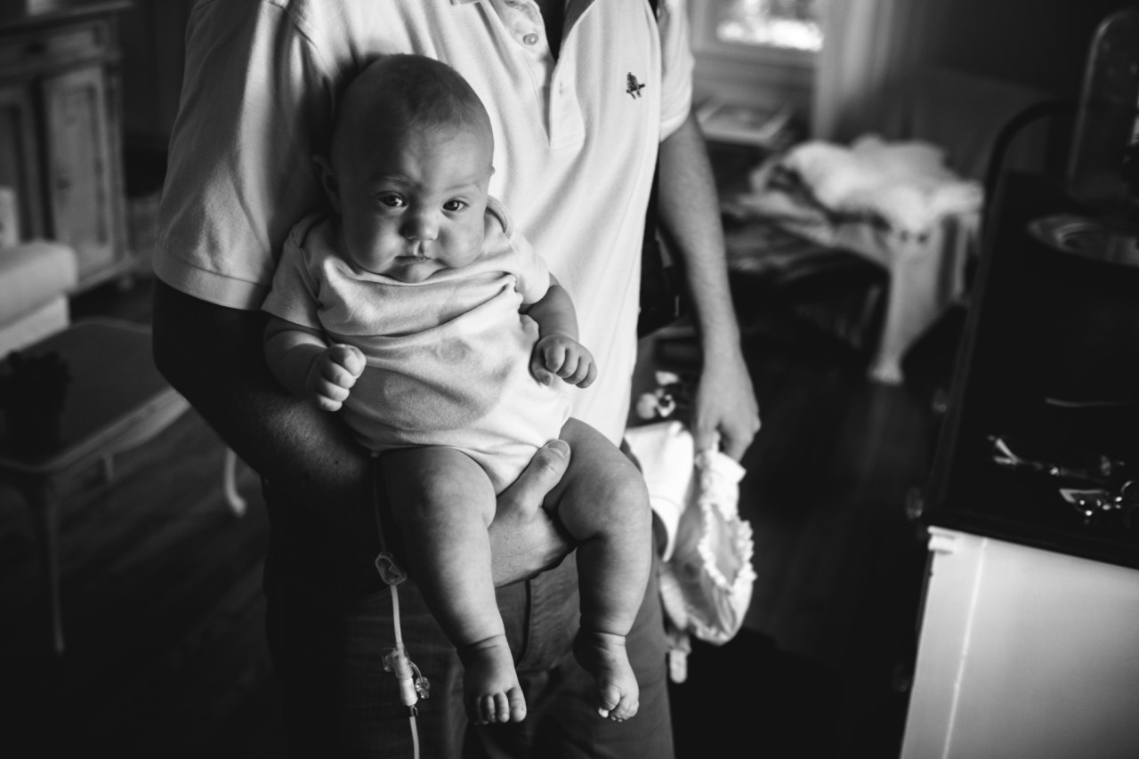 black and white photograph of dad holding baby son looking at camera