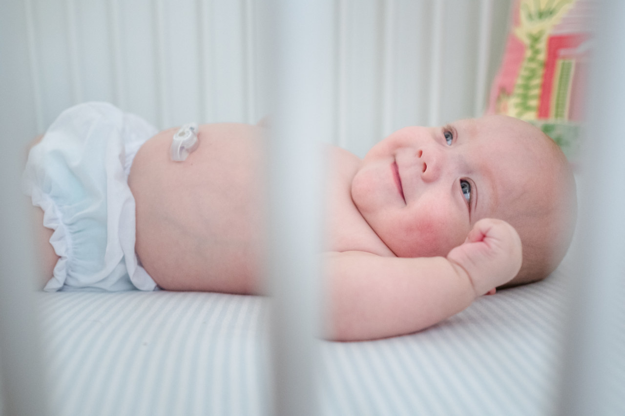 peeking at newborn smiling baby boy through the crib rails