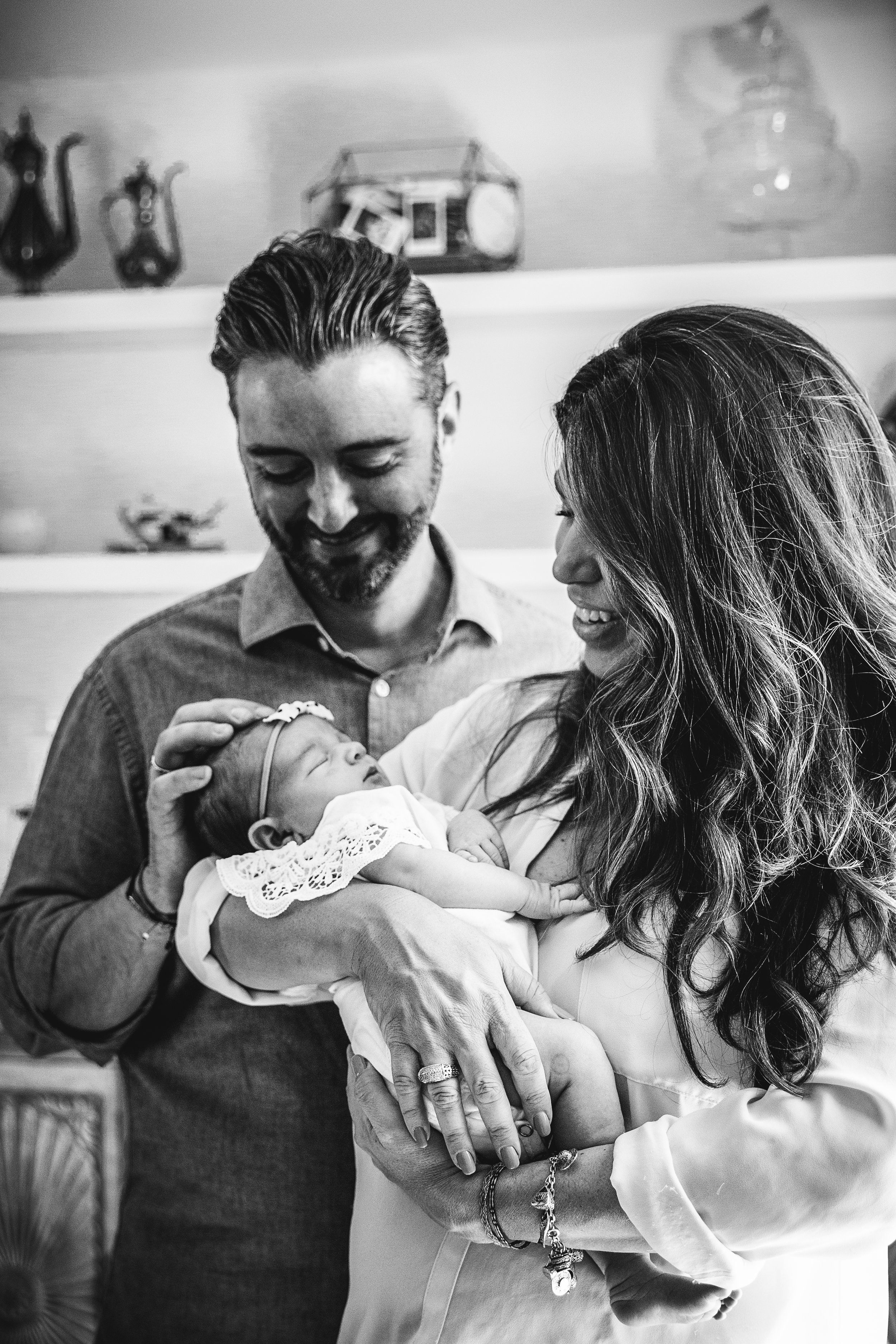 black and white photo of new parents adoring their newborn daughter by window light
