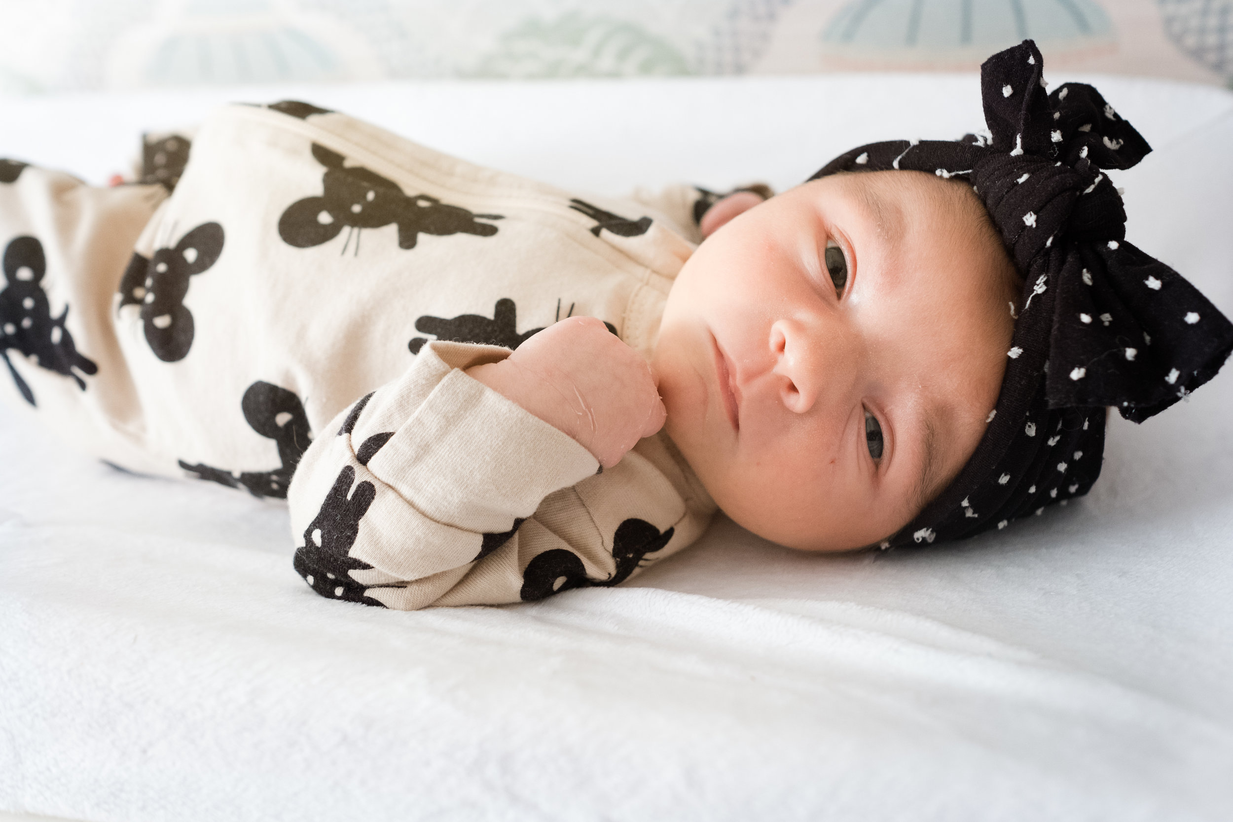 newborn baby girl in black and white outfit on changing table with eyes open