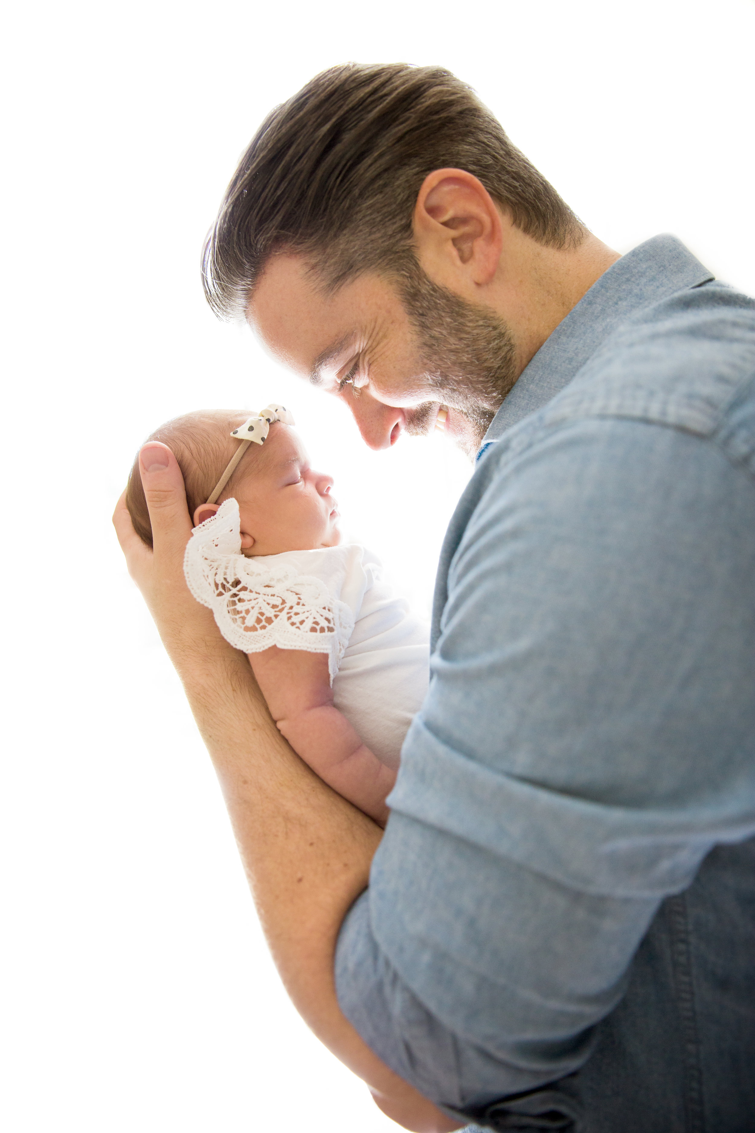 father holds newborn baby girl in profile photograph 