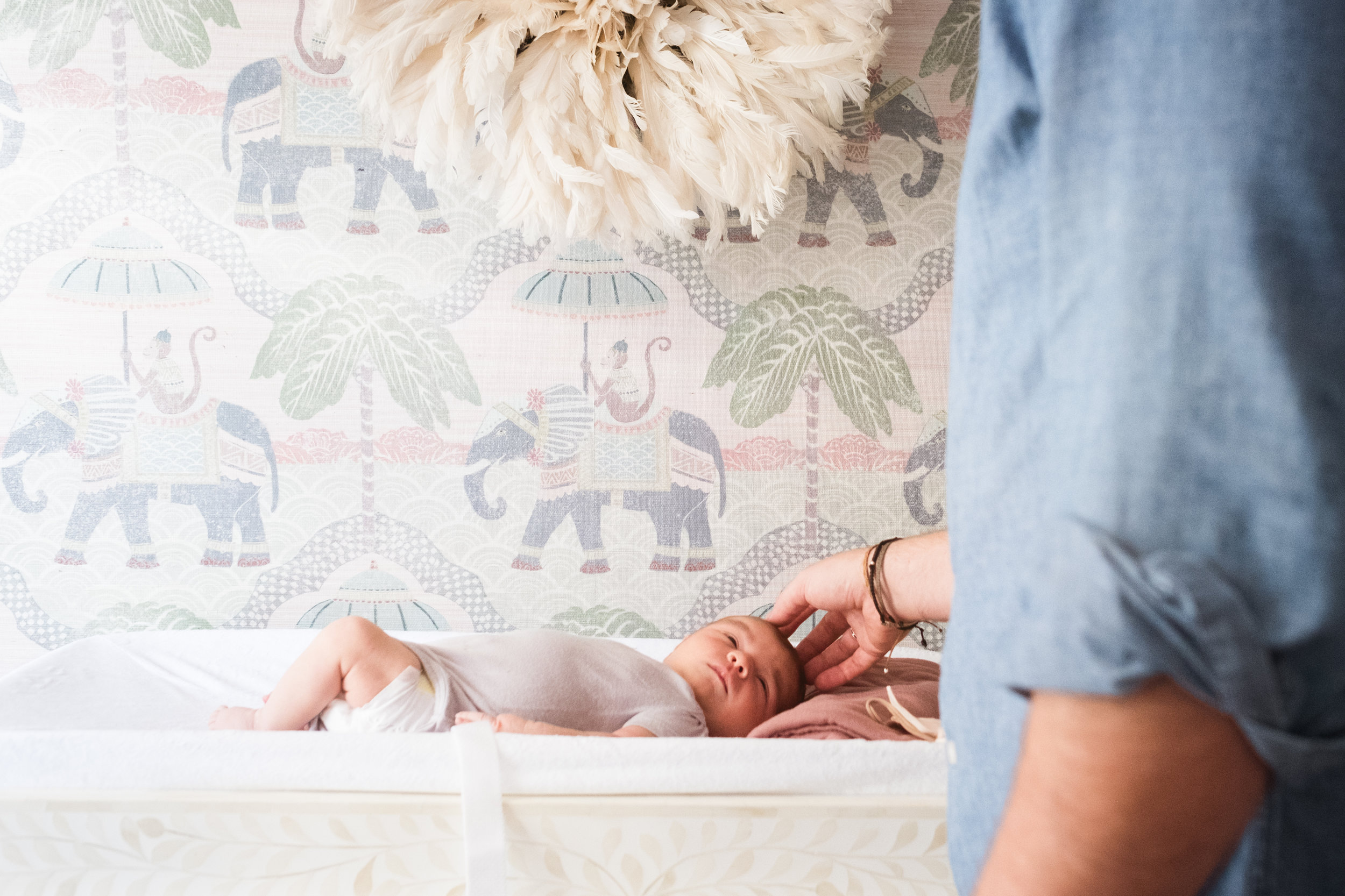 father plays with infant daughter on nursery changing table