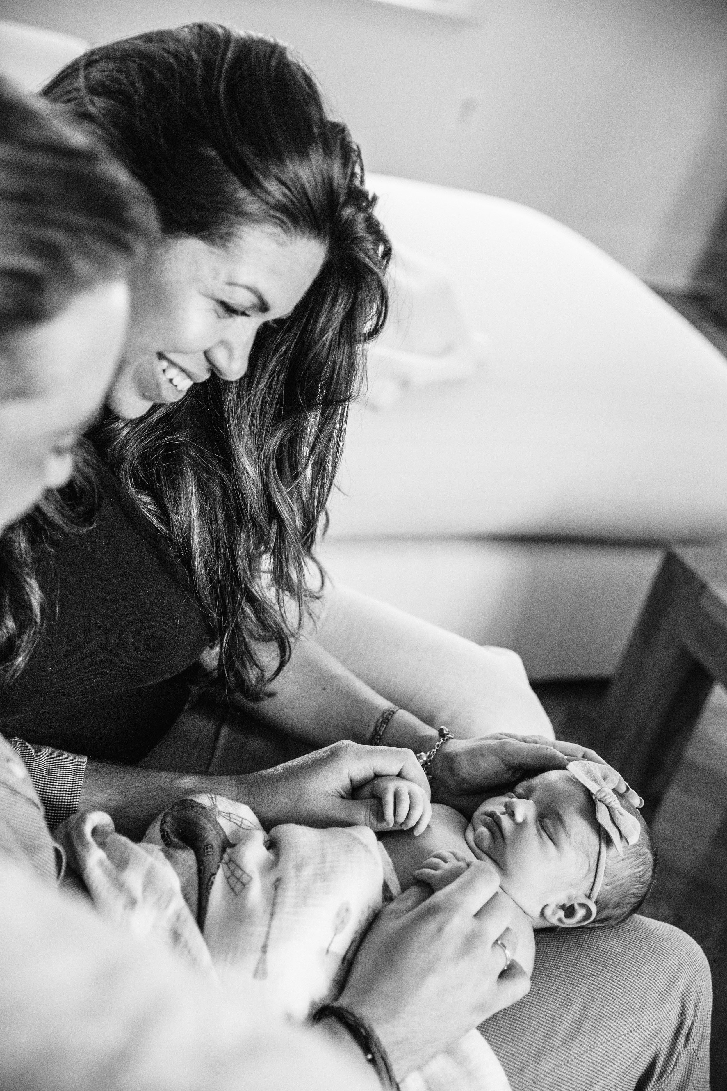 black and white lifestyle photograph of parents playing with newborn daughter