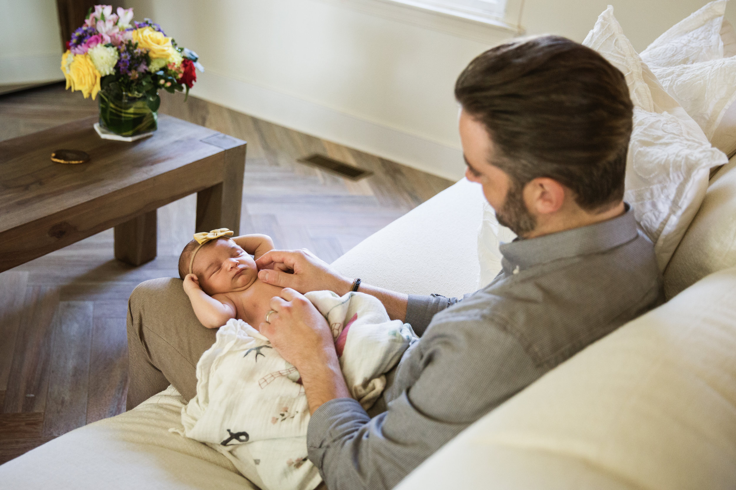 colorful photograph of father playing with newborn baby daughter in stylish living room