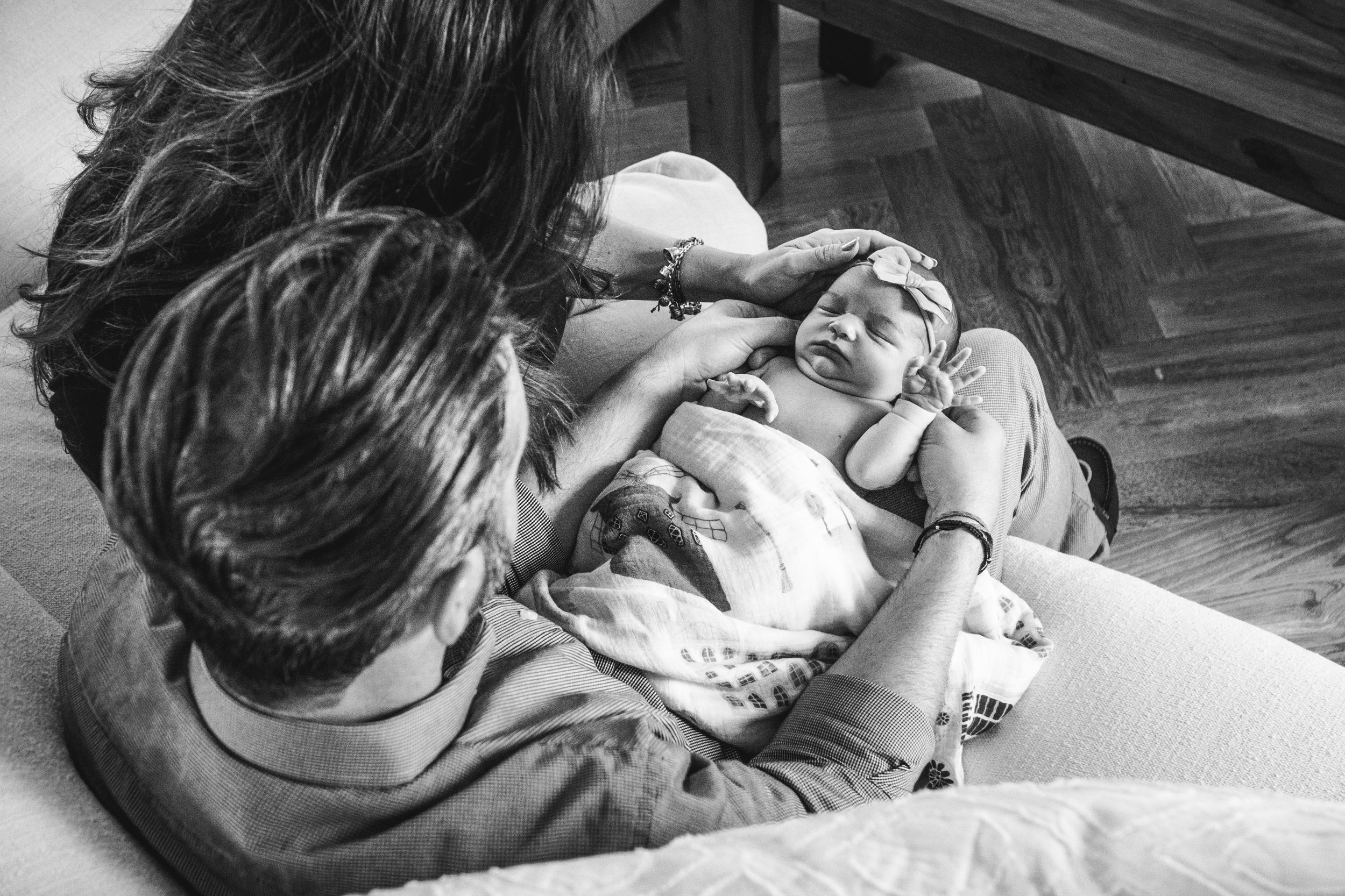 black and white photog of prints adoring newborn daughter on sofa