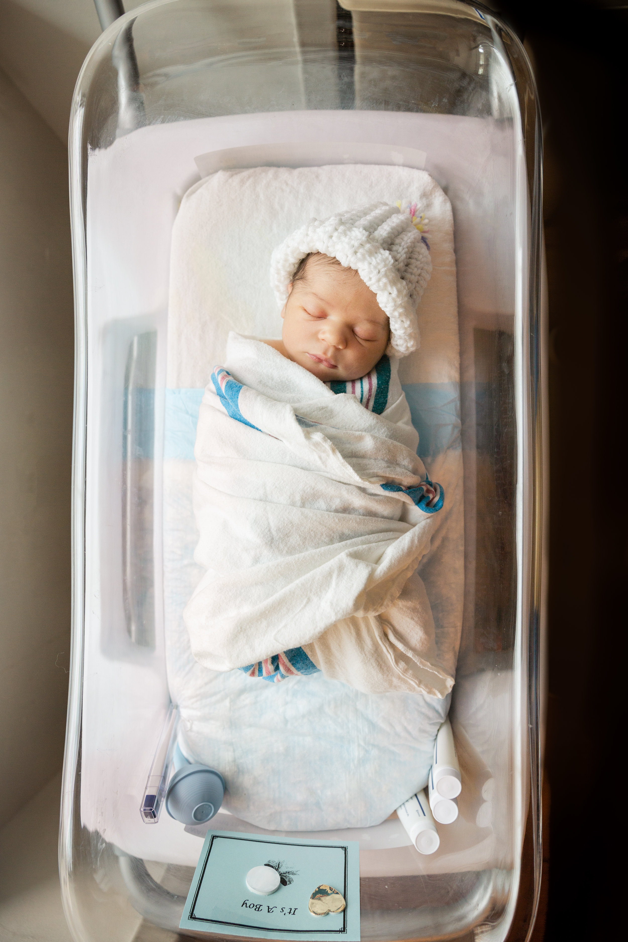 photograph of infant baby boy from above in hospital bassinet