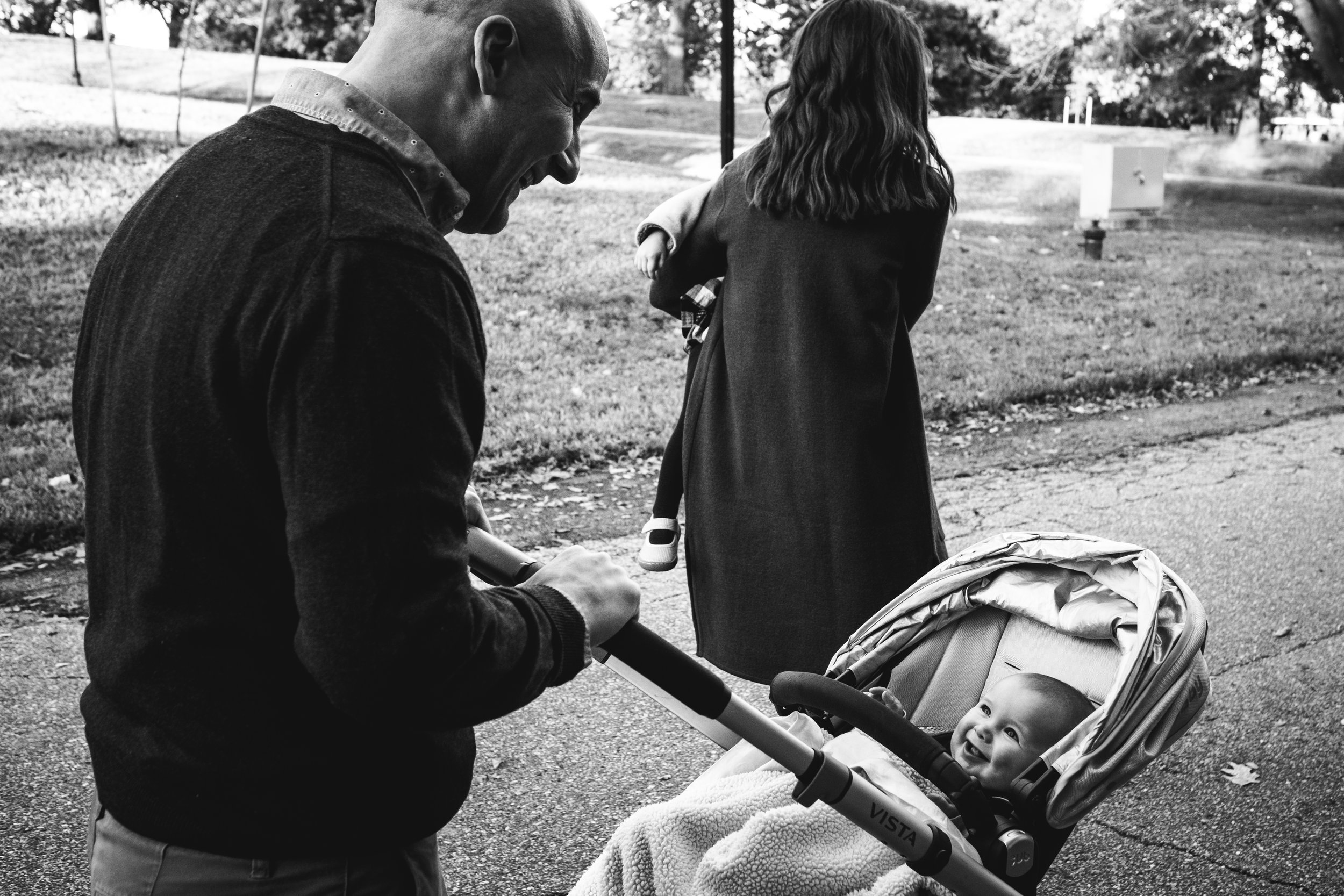 black and white photograph of dad peeking at baby son in stroller