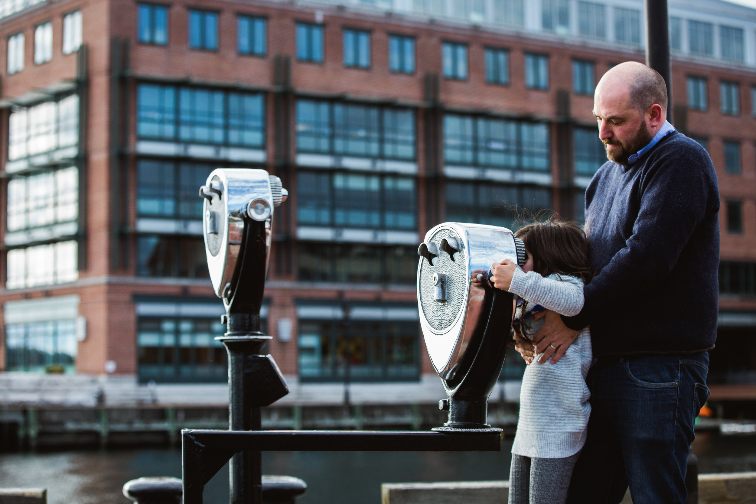 Father helps daughter look through viewfinder at Baltimore Fells Point Pier