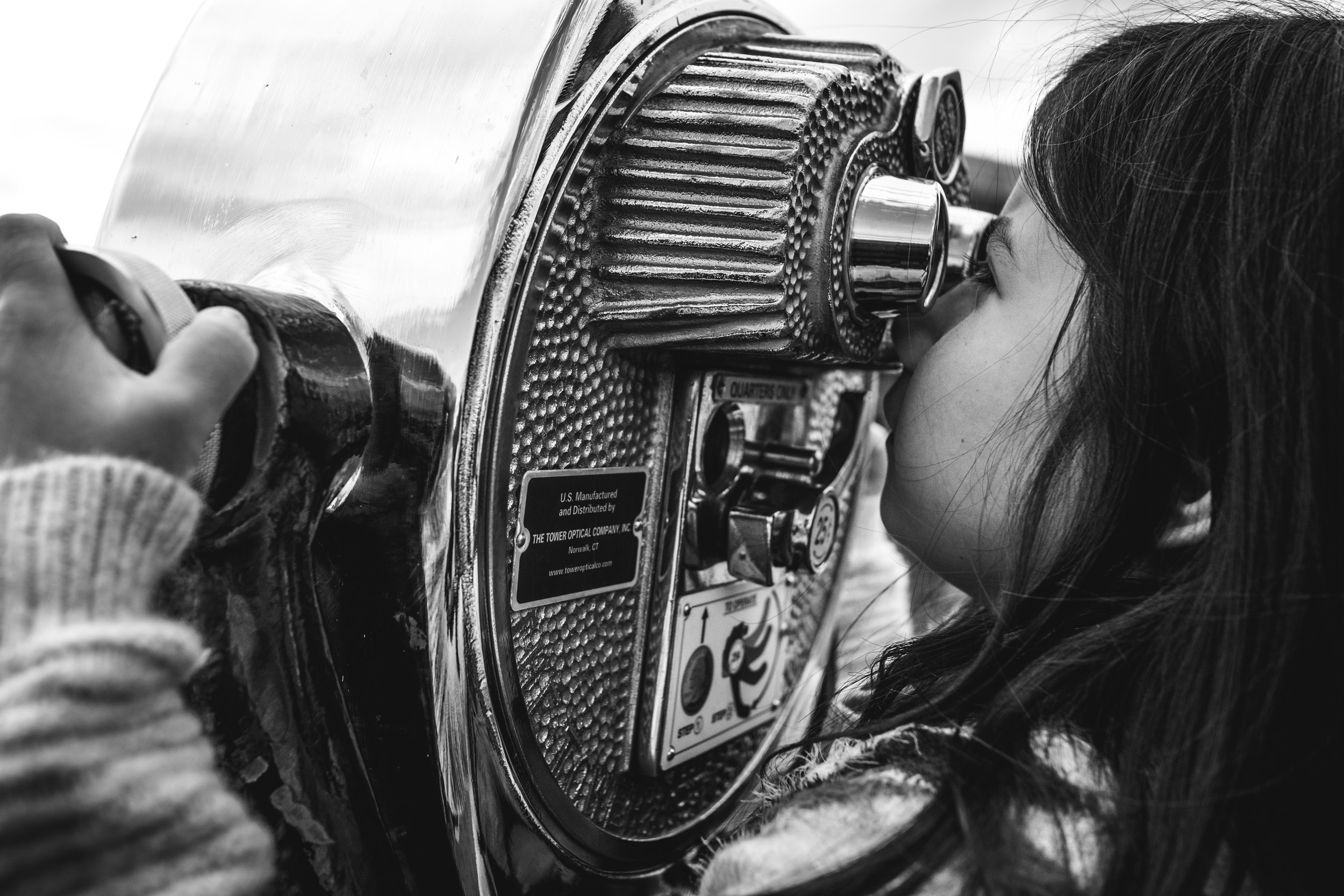 girl looks through city viewfinder at view of Baltimore Harbor