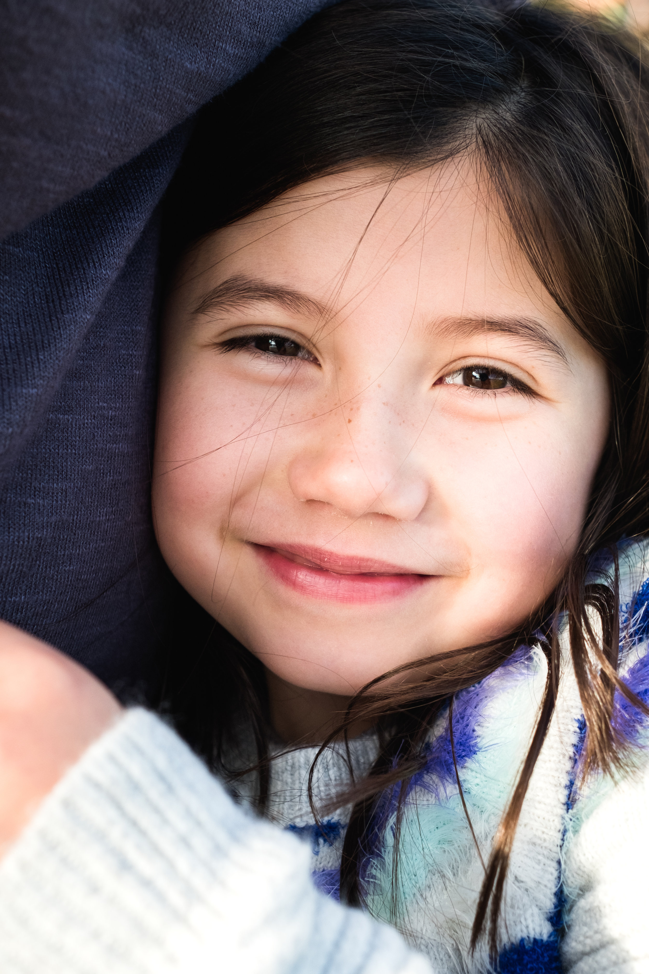 up close portrait of little girls face as she hugs parent