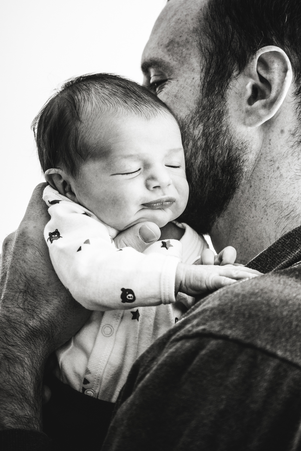 photograph of young father lifting his sleeping newborn daughter to his shoulder