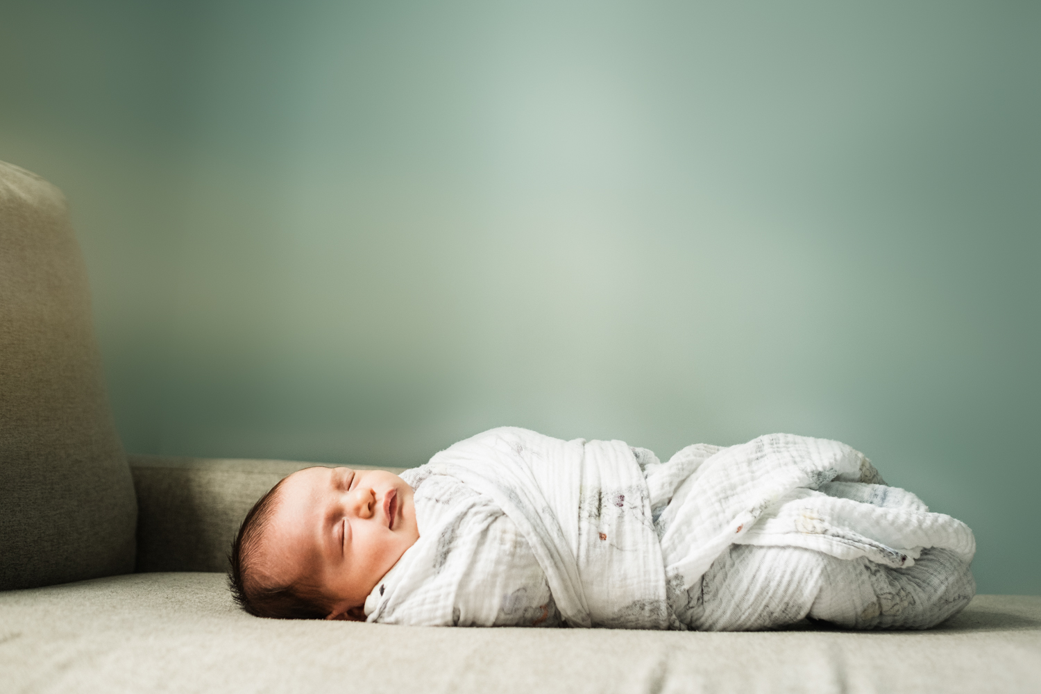 lifestyle newborn portrait of infant swaddled near blue wall