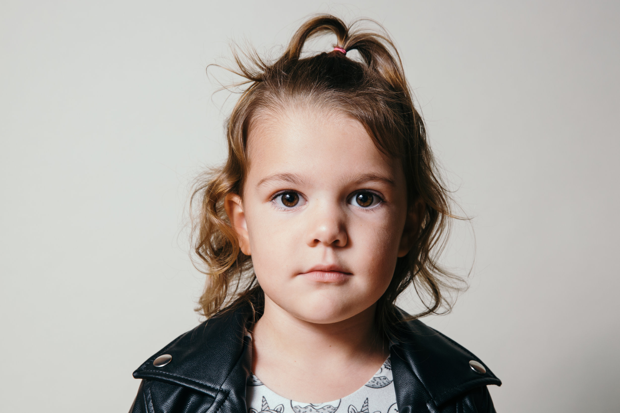 Studio portrait of face of little girl in black leather jacket.