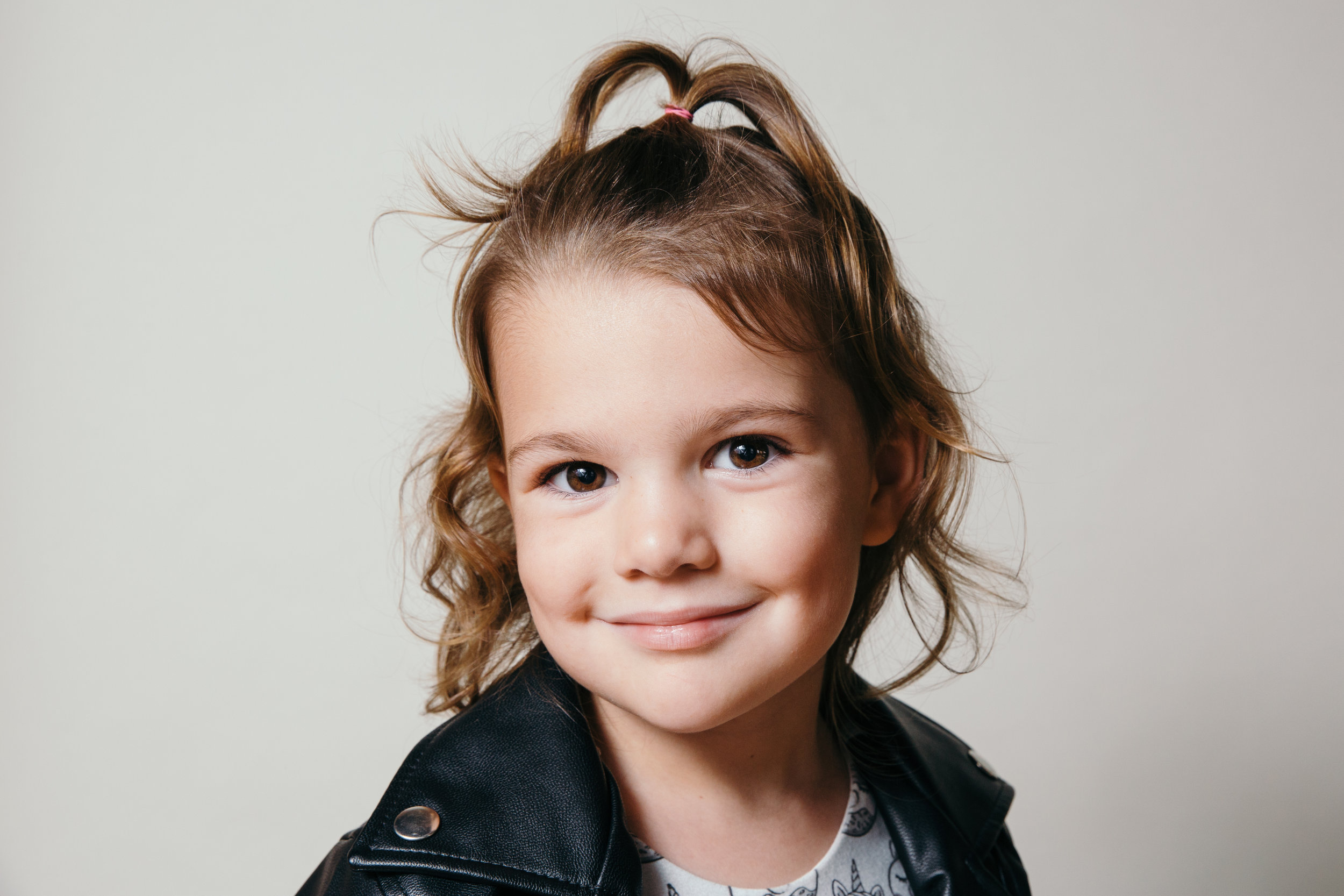 studio photograph of cheeky little girl grinning at camera