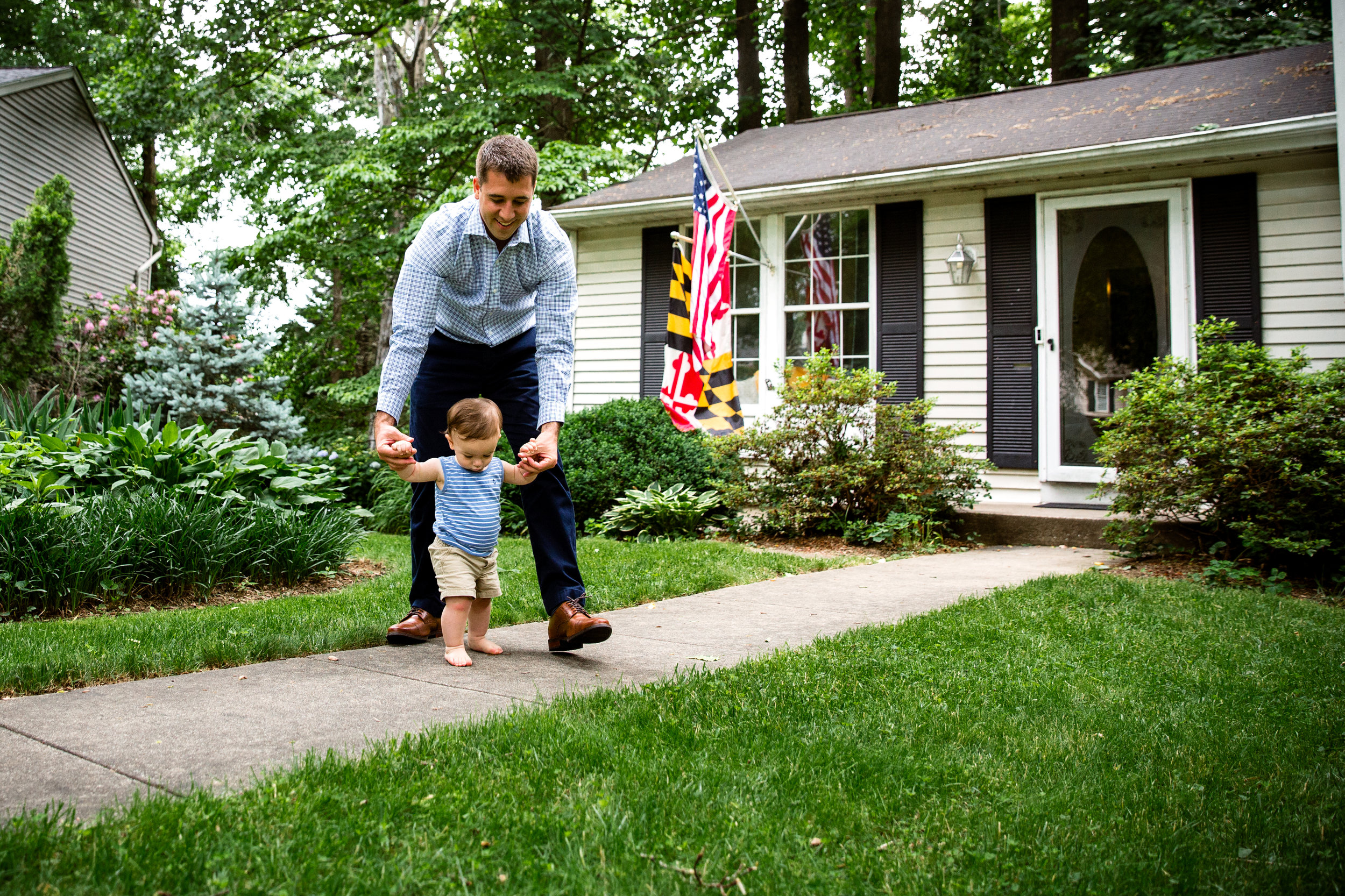 documentary family photograph of dad helping son walk outside grandparent's suburban home