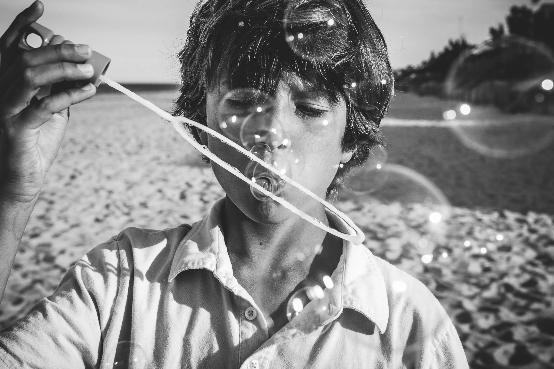 black and white photograph of boy blowing bubles on the beach-200.jpg