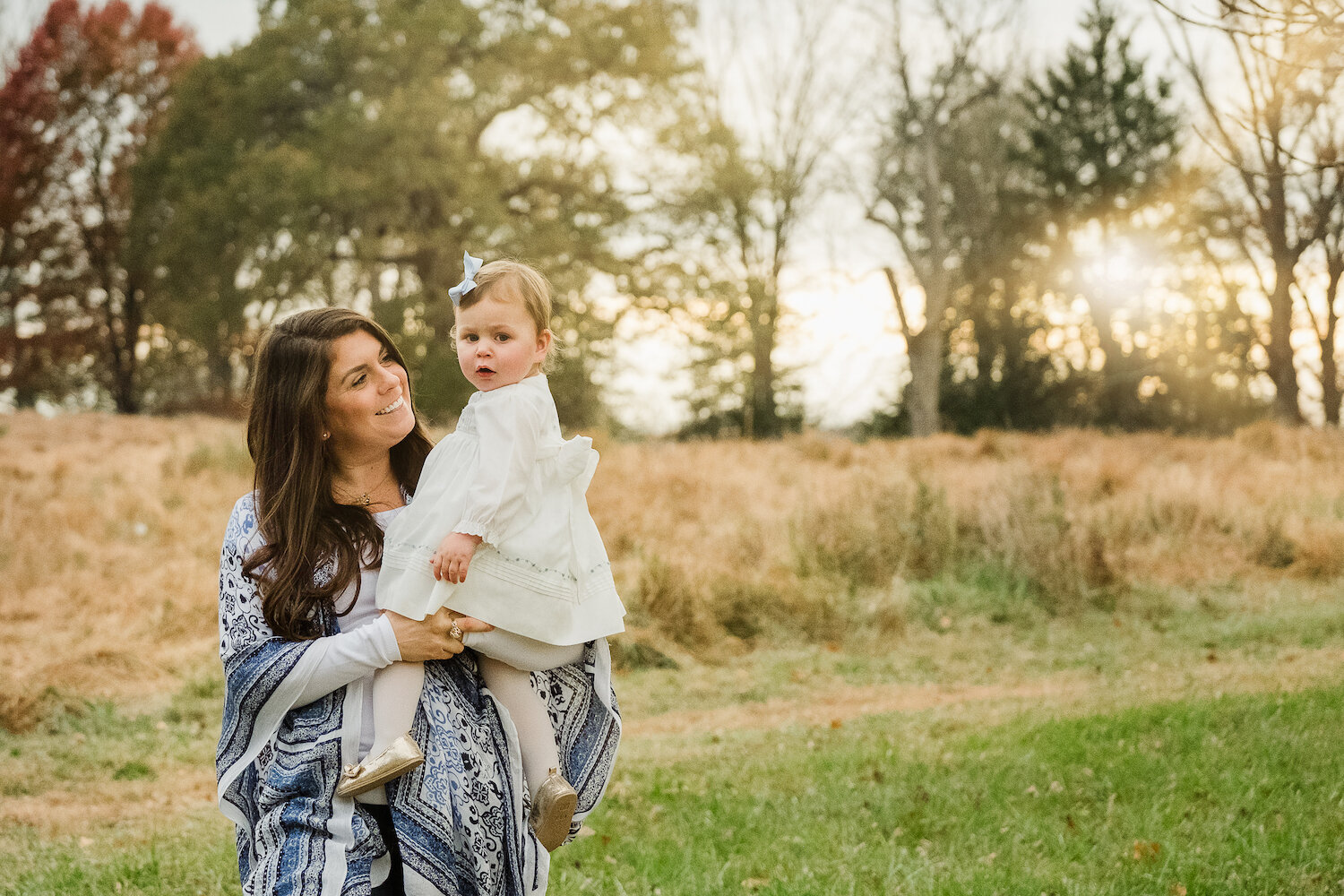 family photograph of mother holding toddler daughter outside in field 