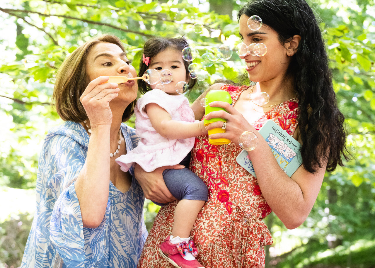 mom-and-grandmother-blow-bubbles-with-baby-girl-on-birthday.jpg