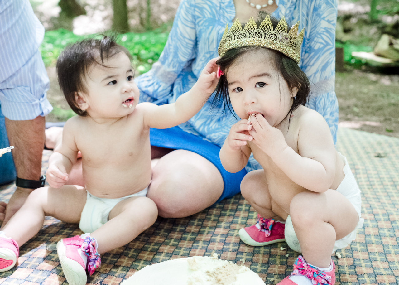 twin-girls-share-birthday-cake-at-party.jpg