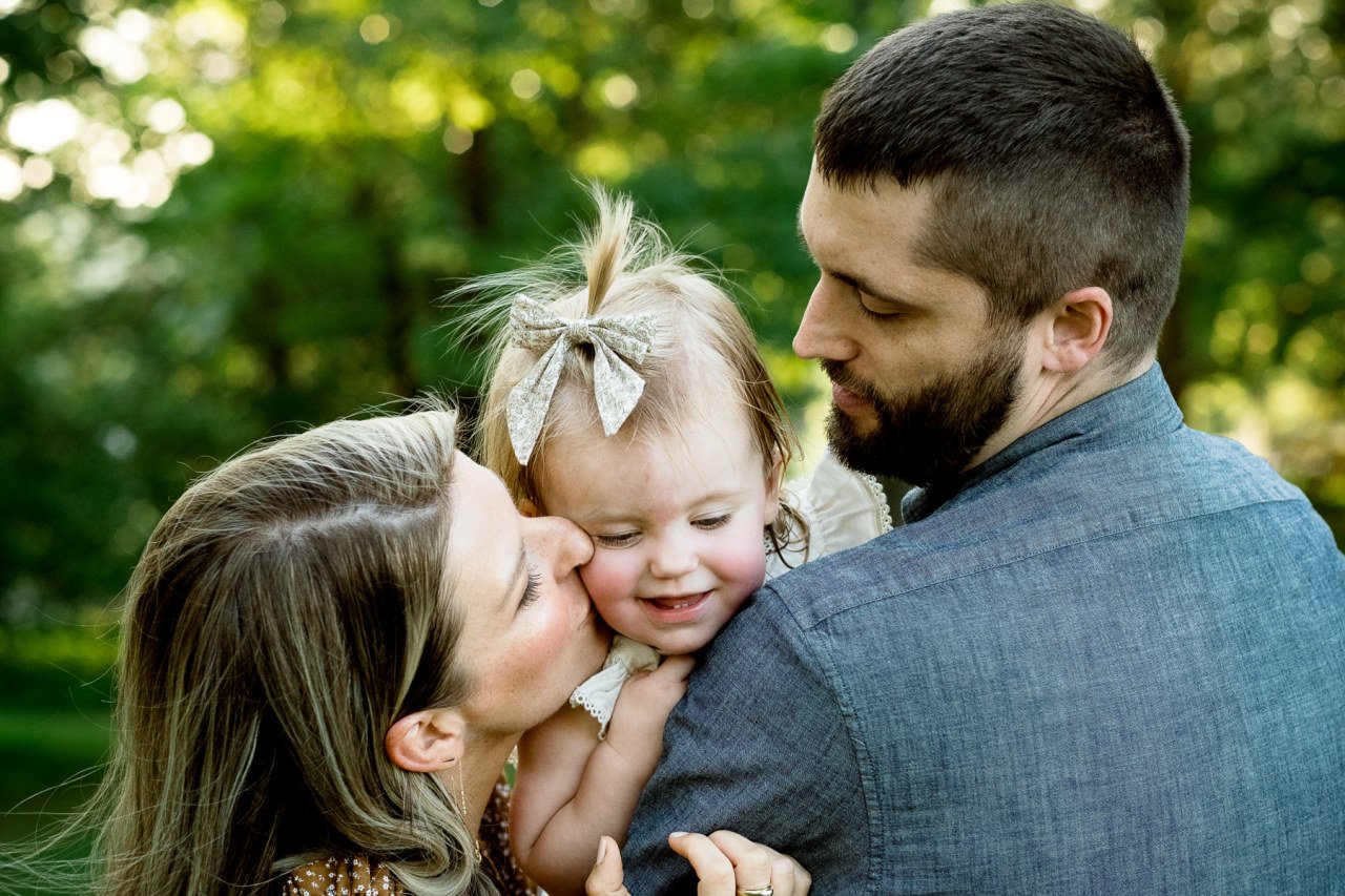 professional family photograph of parents holding and snuggling beautiful daughter