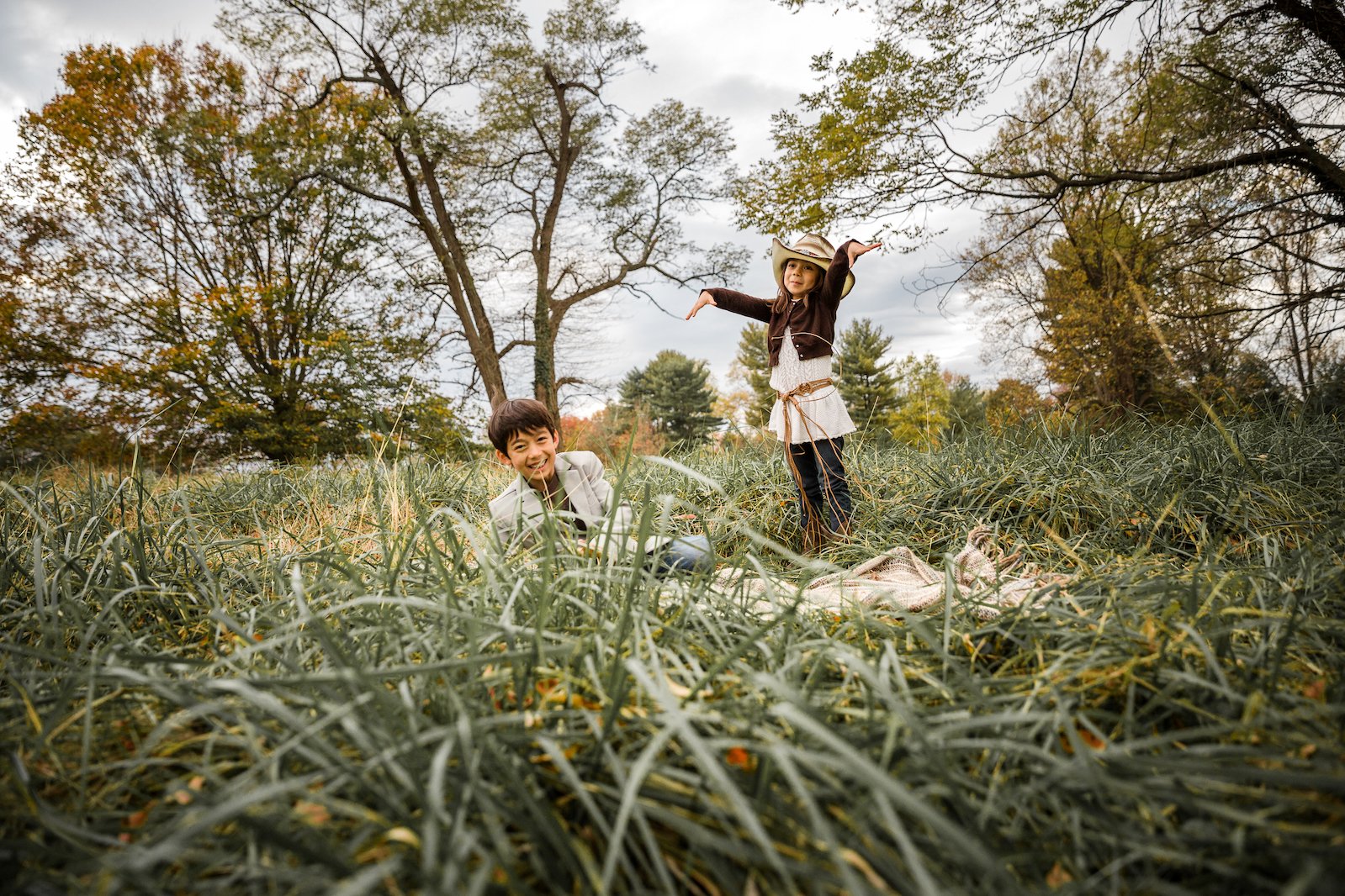 brother and sister play in grass