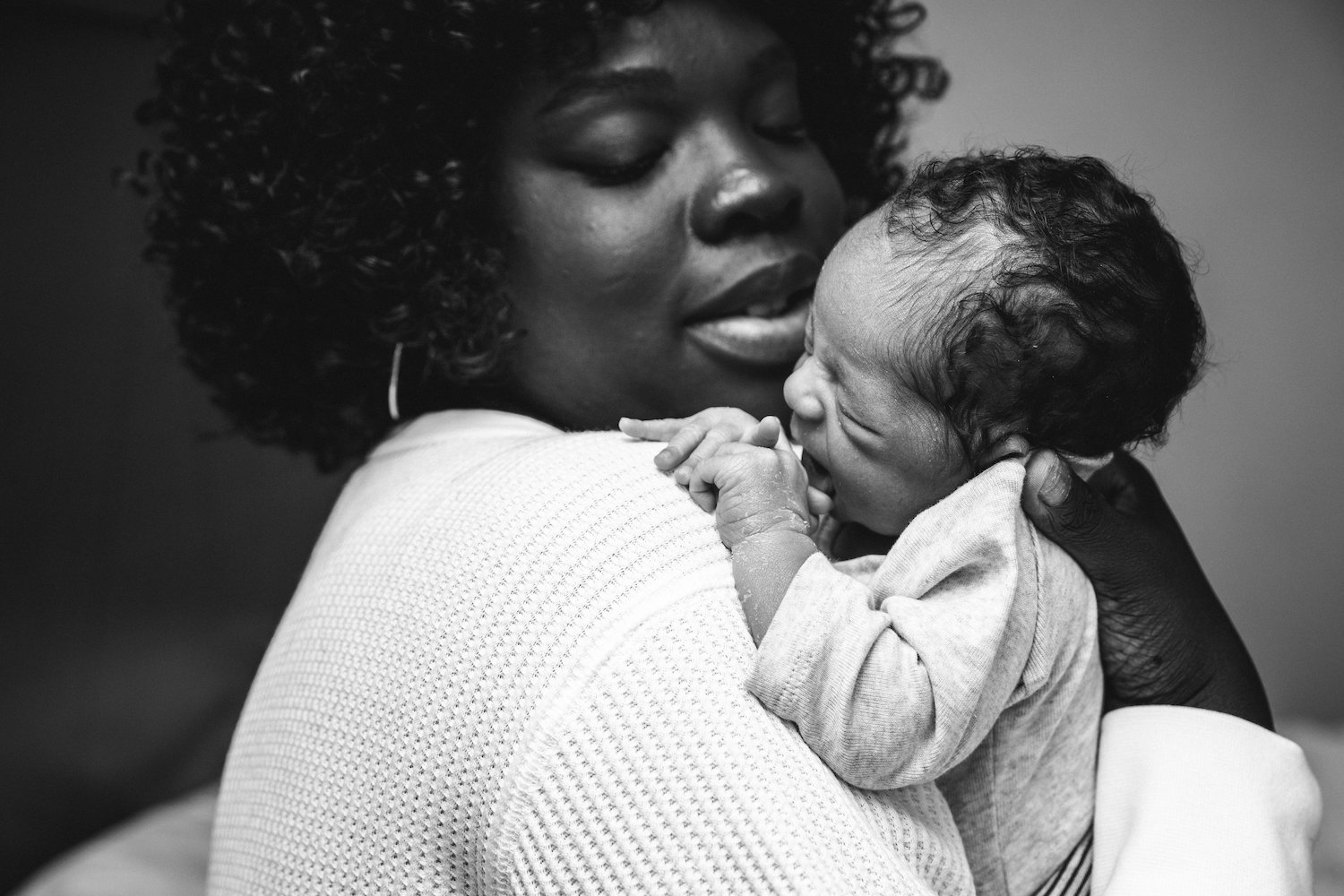 mother holds newborn son by shoulder