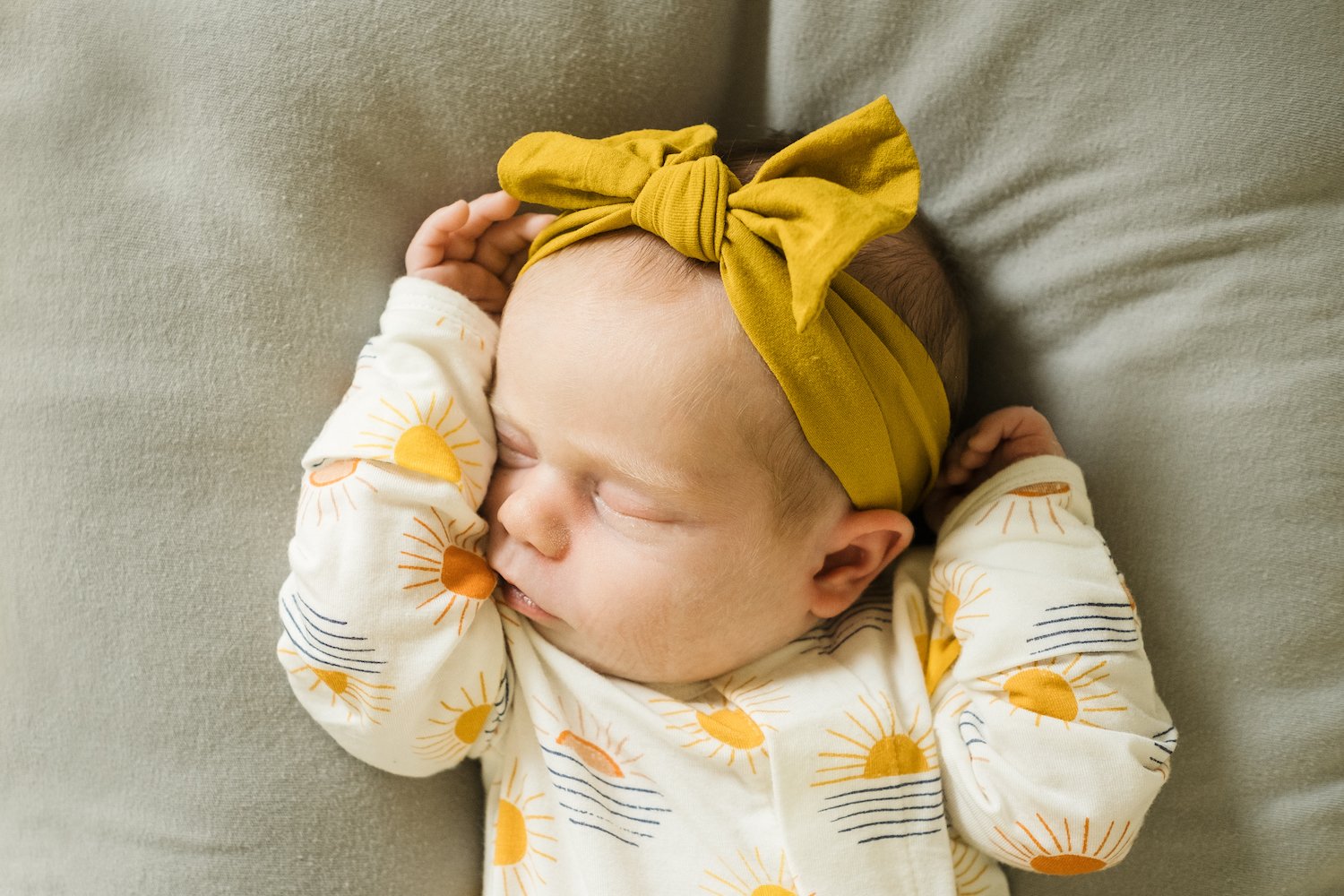 newborn wearing yellow bow is sleeping