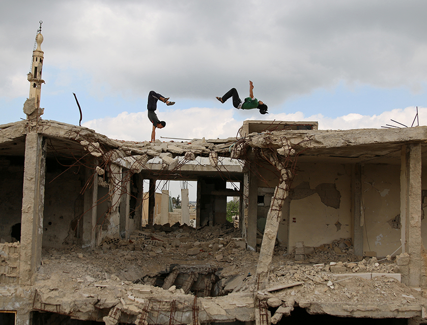 Ibrahim al-Kadiri and another parkour practitioner demonstrate their skills on damaged buildings in Inkhil, Syria. 