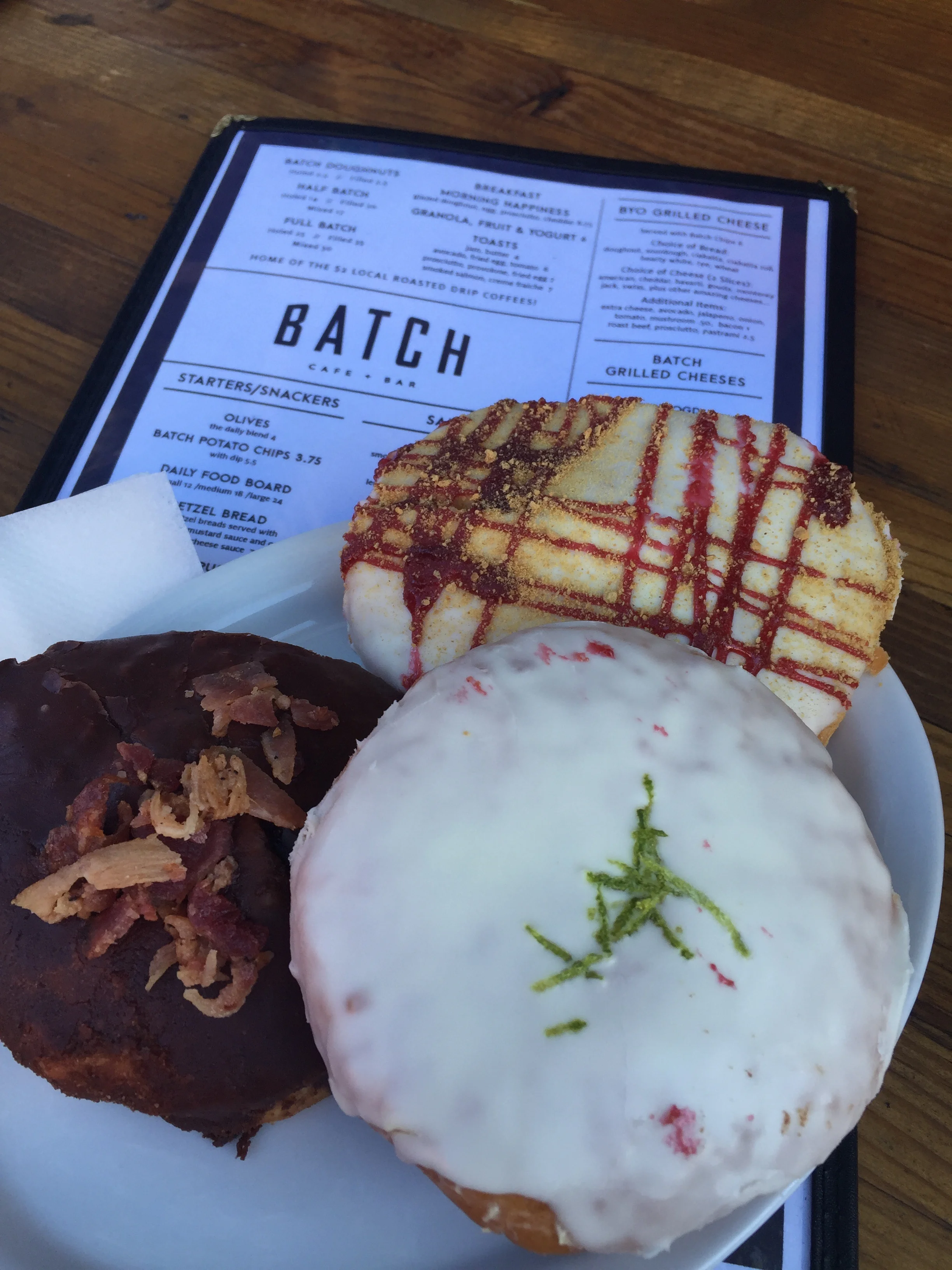 White chocolate raspberry donut, bourbon bacon Boston cream donut, and key lime donut
