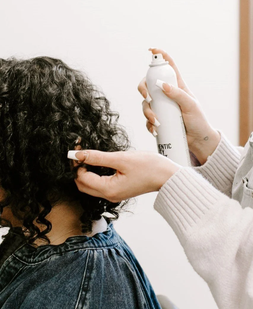 Siren stylist spraying product to curly haired client
