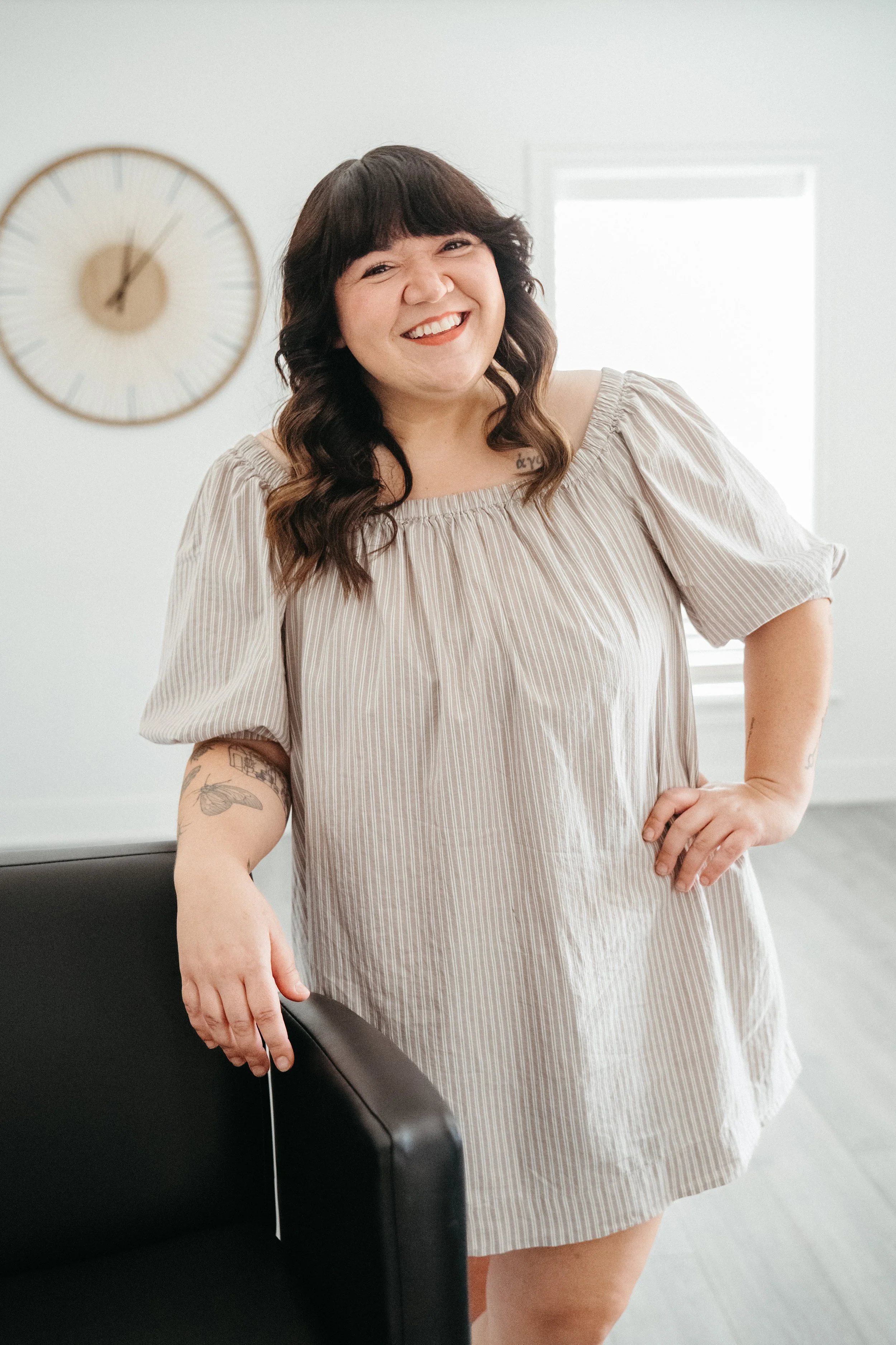Jackie, a Siren hairstylist, smiling while leaning against the back rest of salon chair inside Siren Curl Studio.