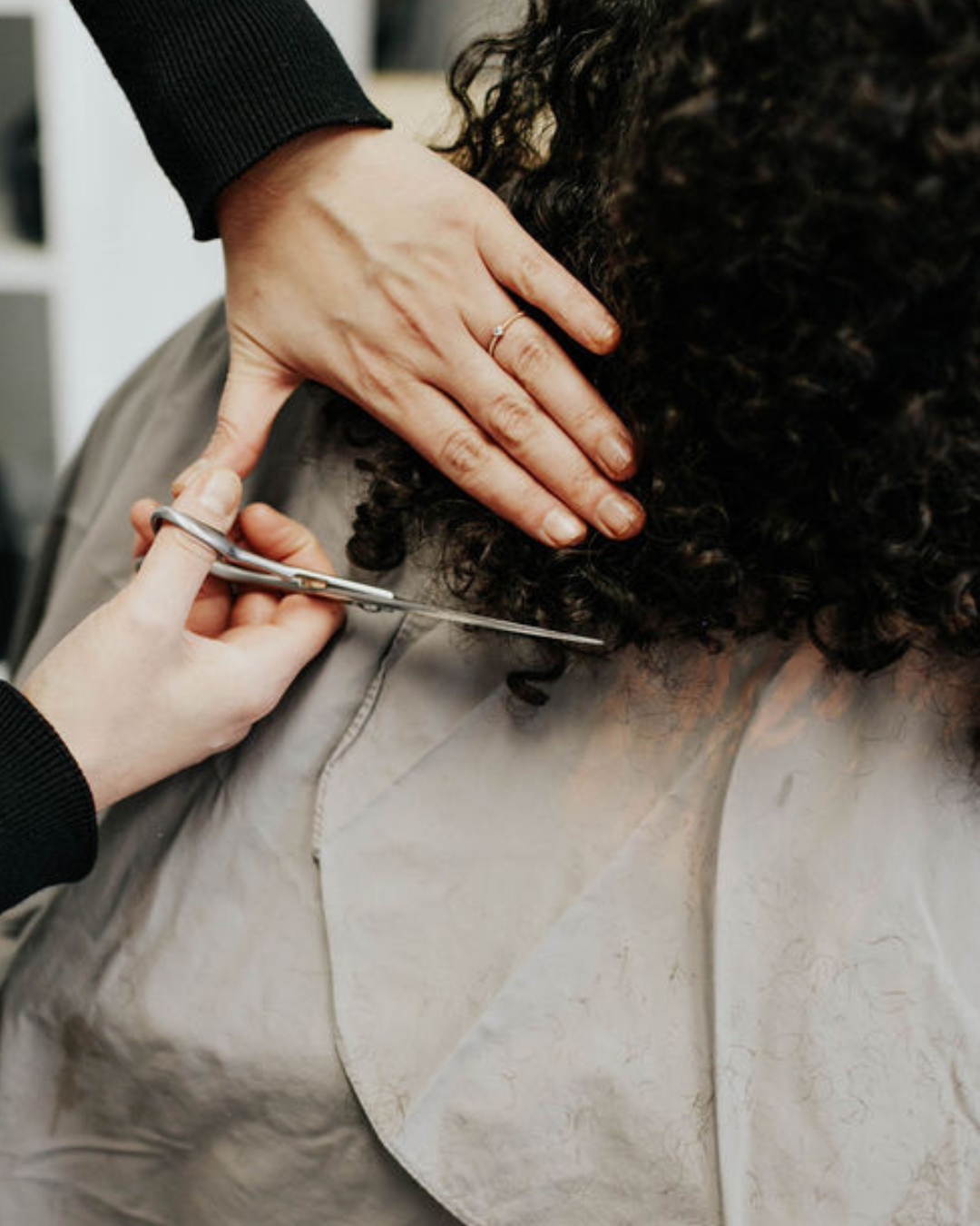 Siren stylist trimming curly hair ends with professional scissors during a precision curl cut at Siren Curl Studio in Tulsa.
