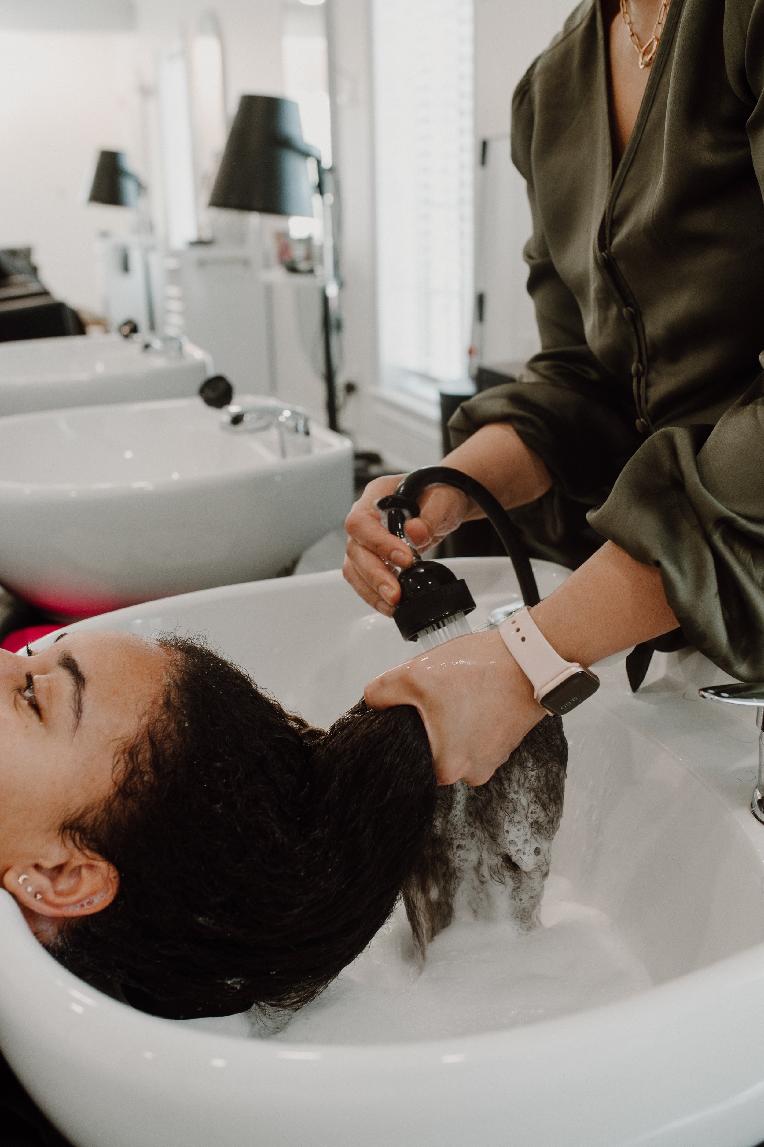 Siren stylist washing a curly haired client's hair at shampoo bowl at Siren Curl Studio in Tulsa.