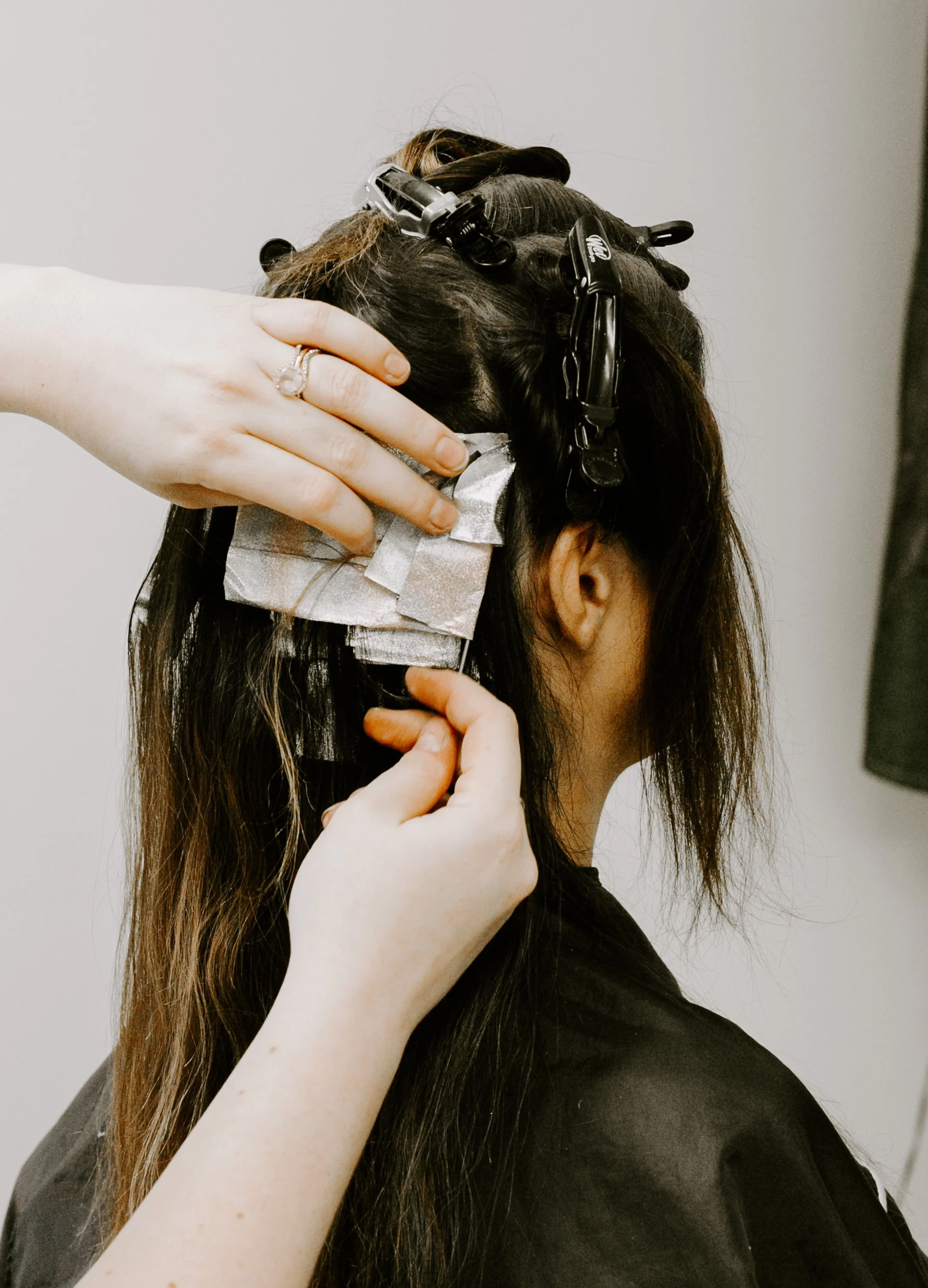 Siren color specialist applying hair color with foils during a professional coloring service at Siren Curl Studio in Tulsa.